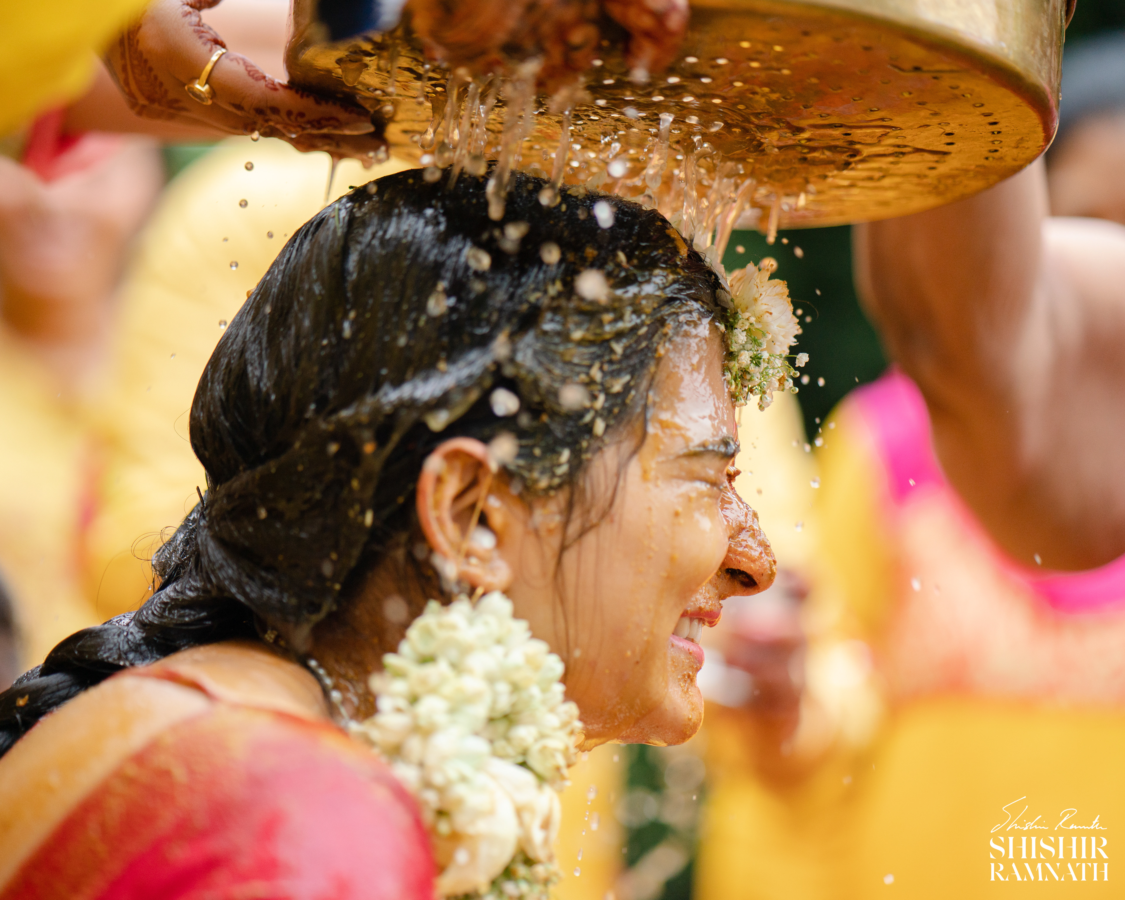 high shutter speed shot of water falling on an indian bride during her haldi ceremony
