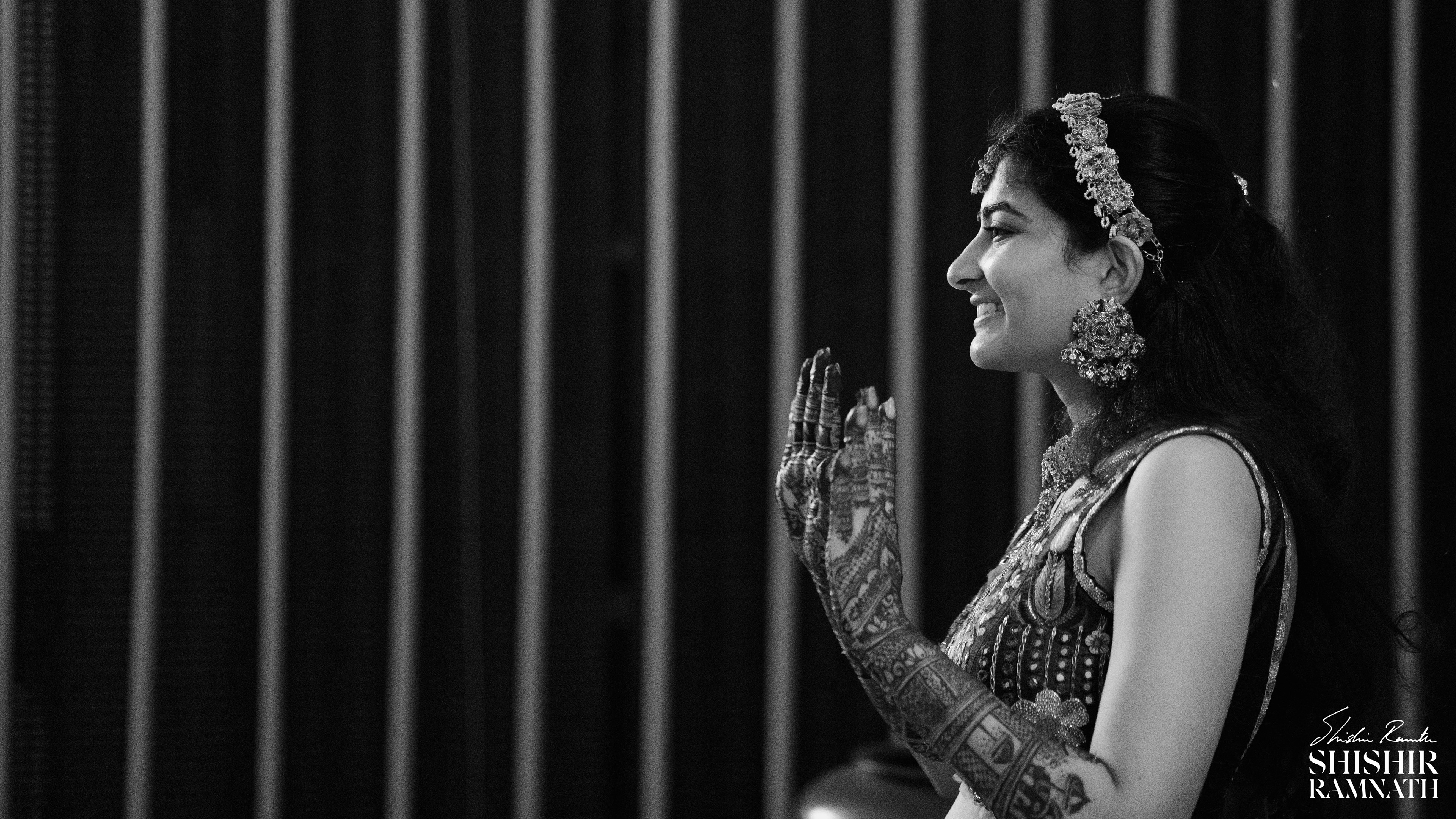 bride lifts up her hands to show her mehndi patterns in a black and white image