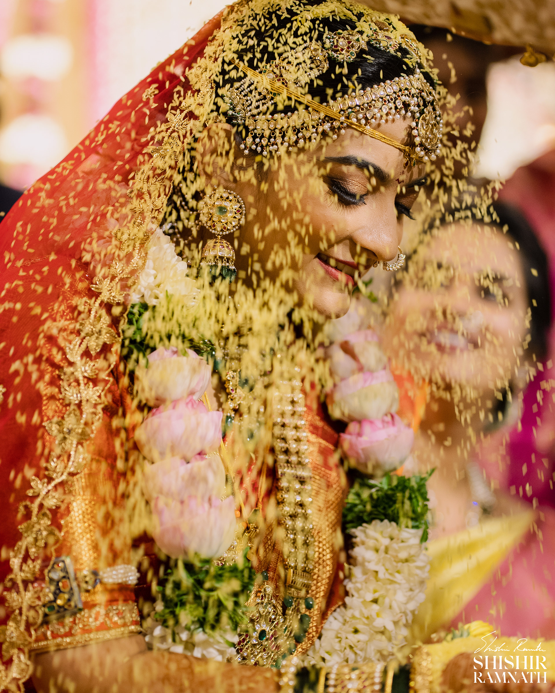 an indian bride closing her eyes as turmeric rice falls on her as a part of indian wedding traditions, photograph by shisihr ramnath