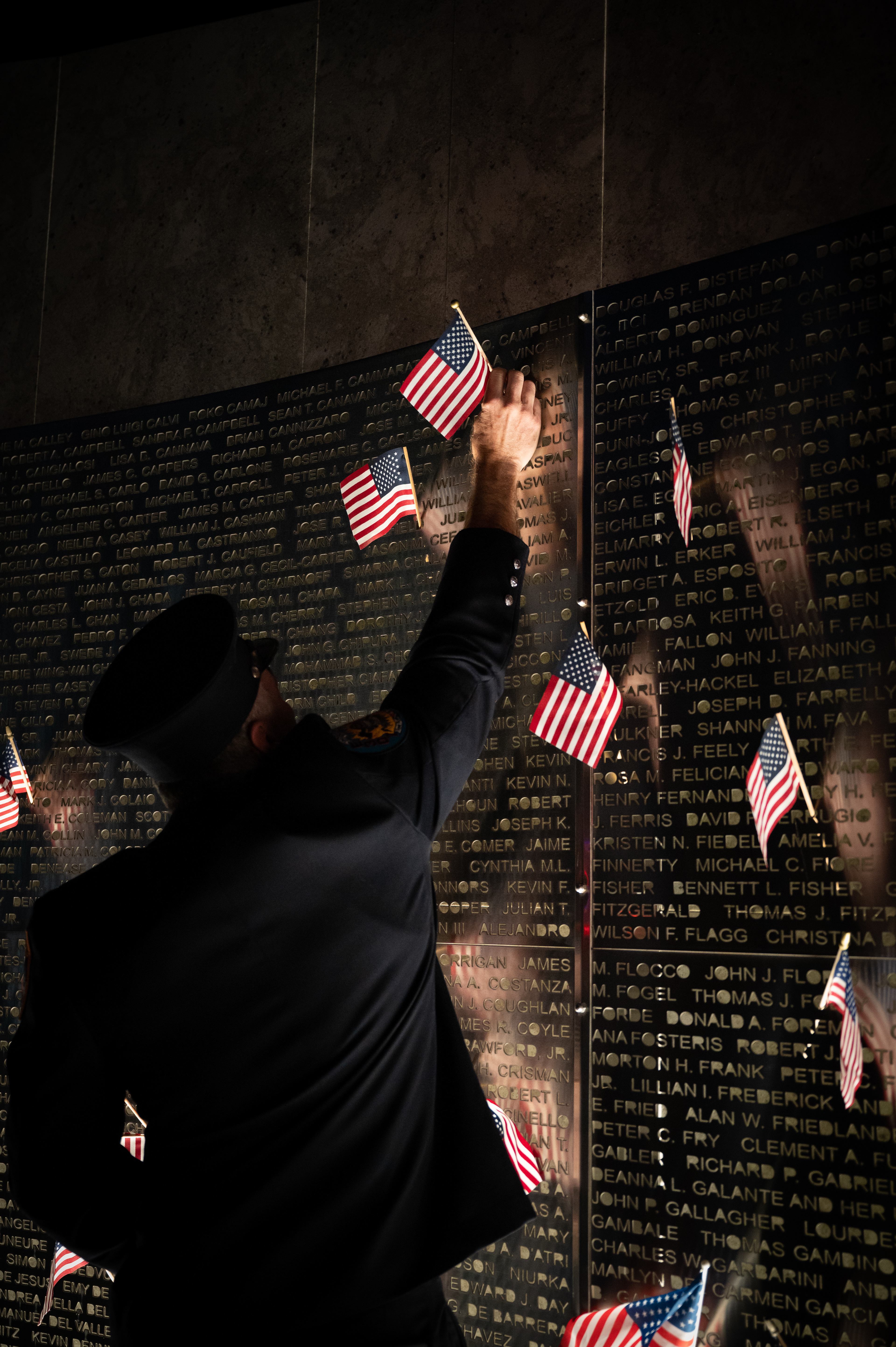 Retired New York City Firefighter Robert Cupani hangs an American flag on the Rocky Point Fire Department's 9/11 Memorial Wall as a means of commemorating the thousands of lives lost on Sept. 11, 2001.