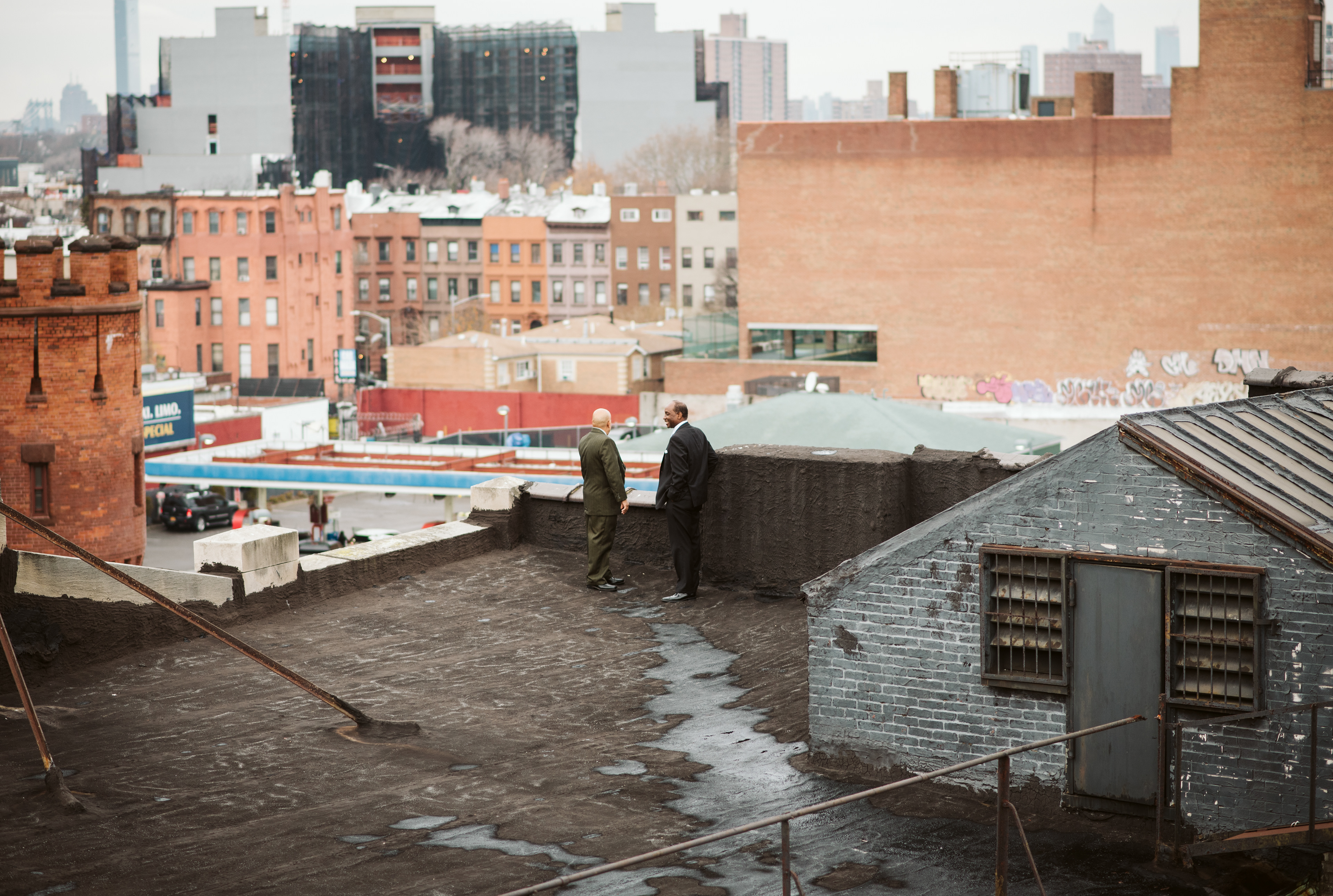 Two men share a laugh while overlooking the New York City Skyline on a rooftop in Crown Heights, Brooklyn.