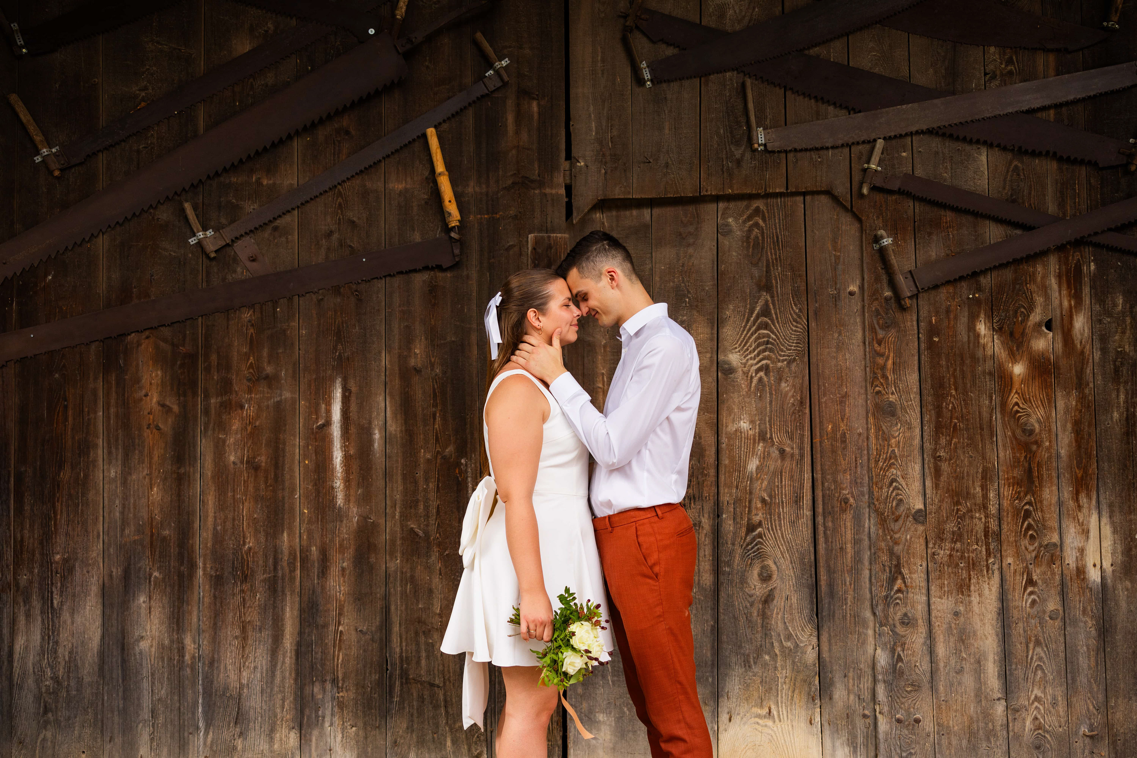 Le couple de marié se tient debout devant une grande porte en bois