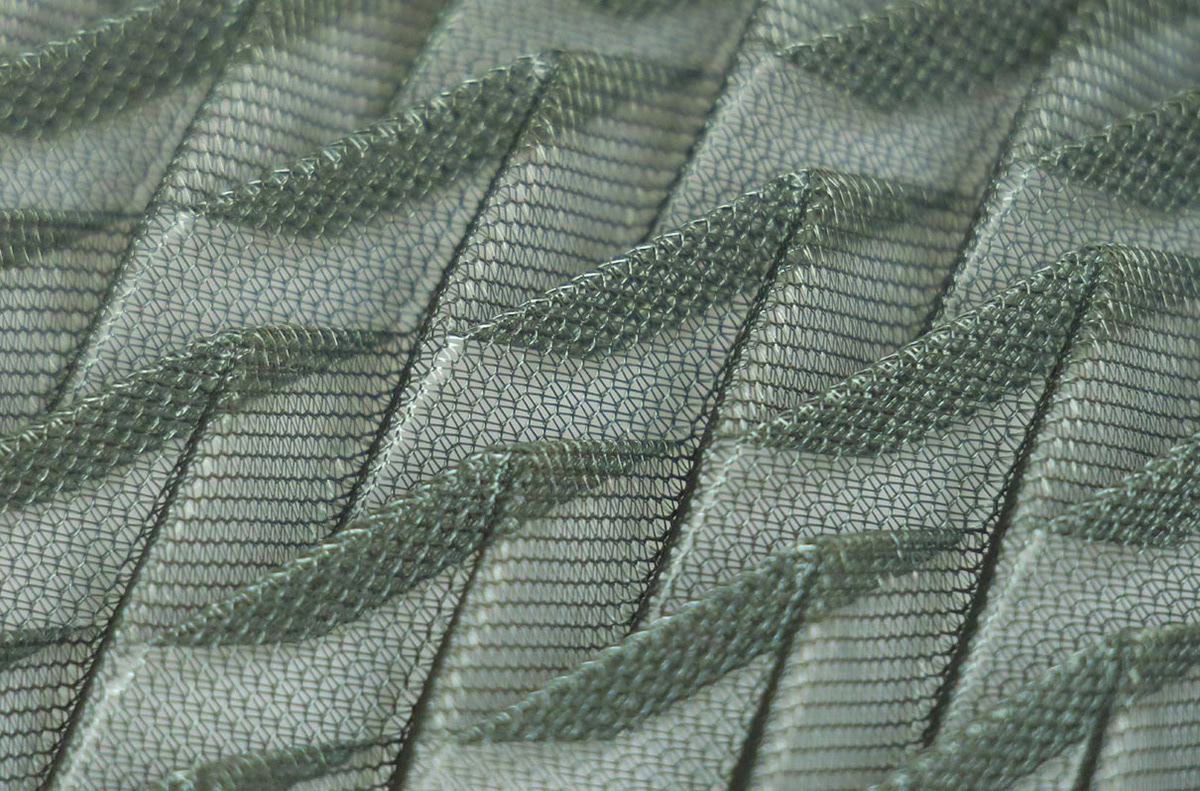 Green synthetic textile manually pleated using folding molds and heat.
