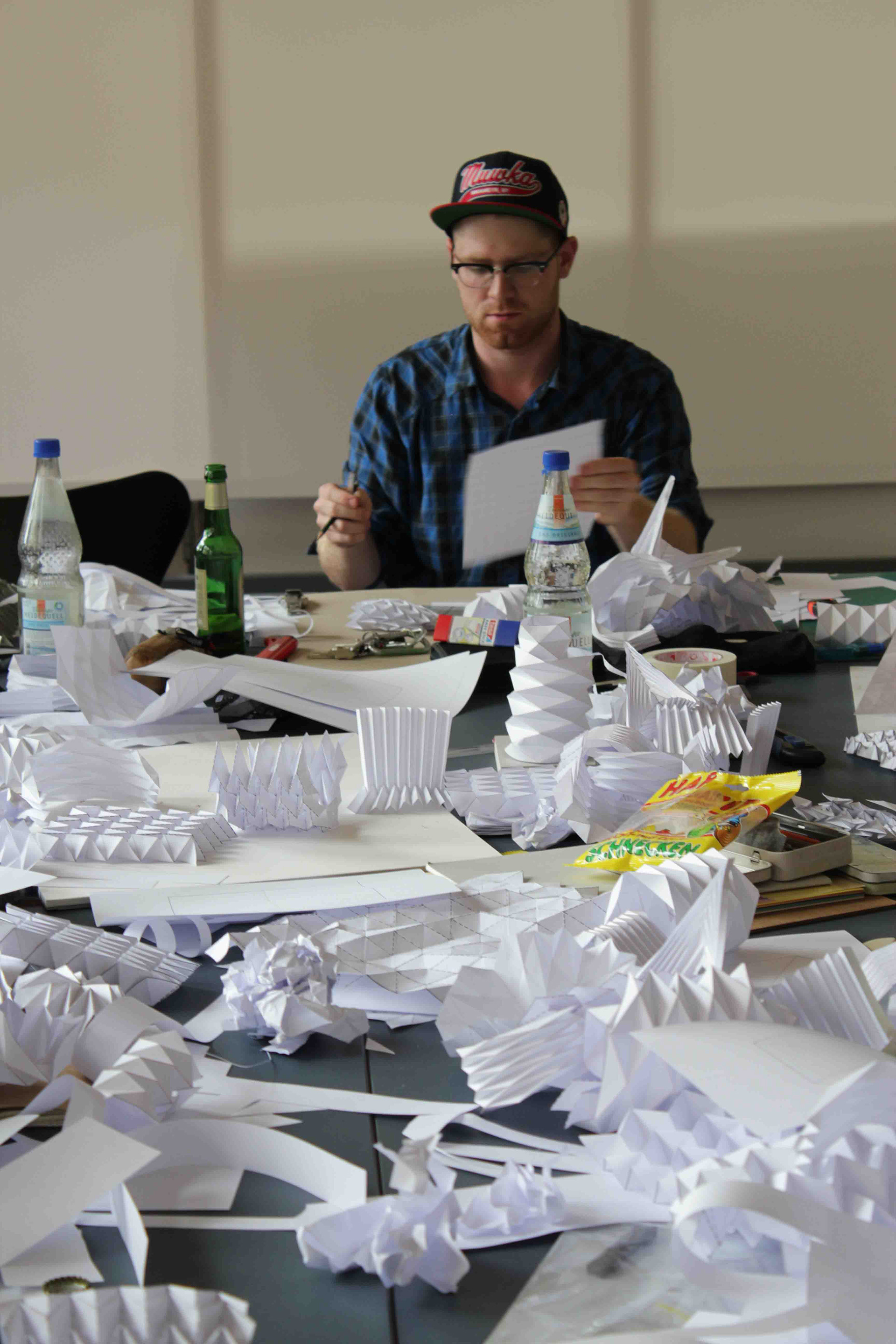 Student with many prototypes and demonstration models during Kristina Wißling's workshop on origami and folding techniques in industrial design.