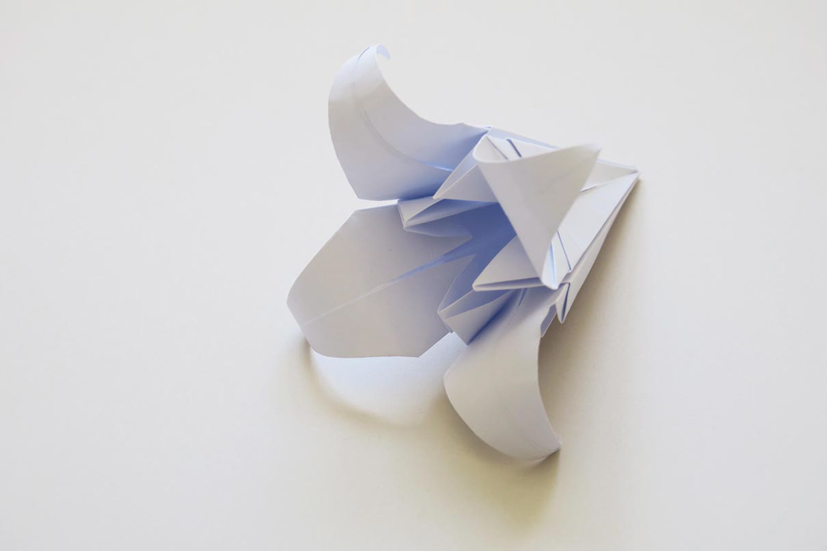 Folded white lily made of origami paper for a trade fair stand as a giveaway.