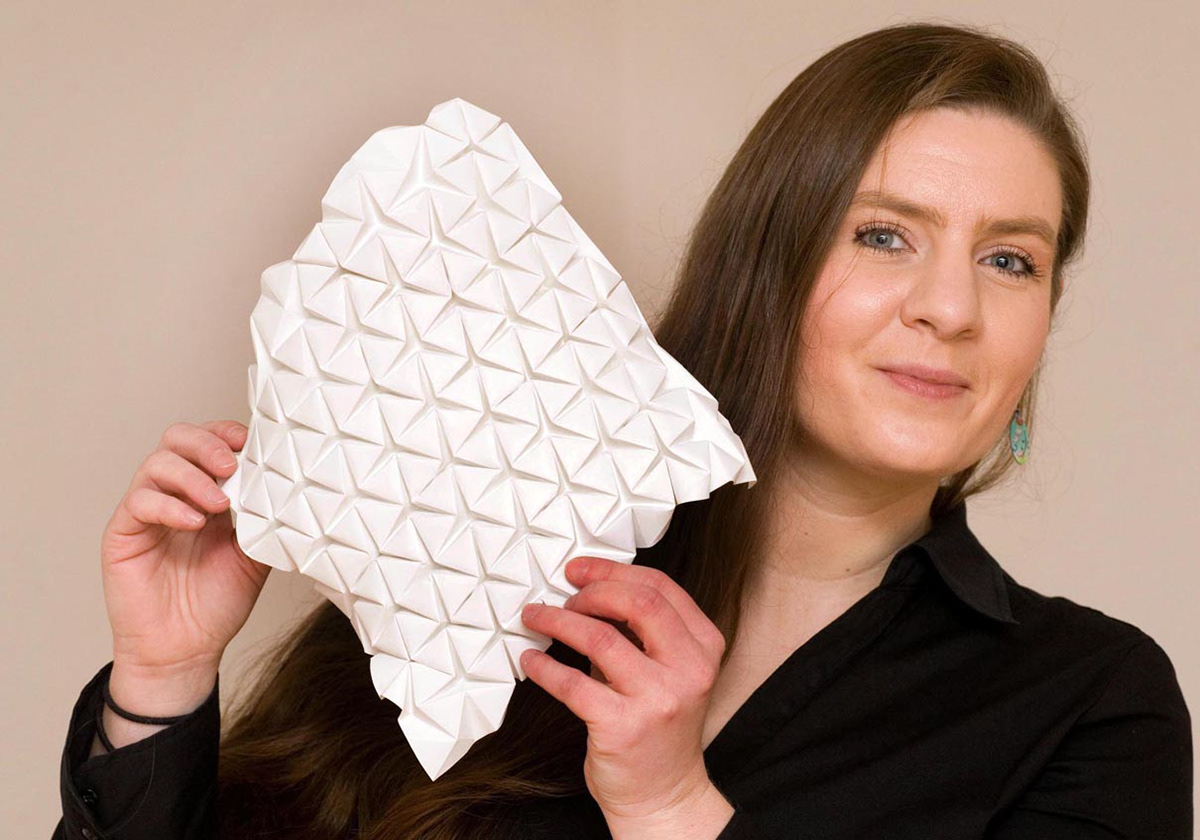 The designer Kristina Wißling with an origami folding structure made of synthetic paper.