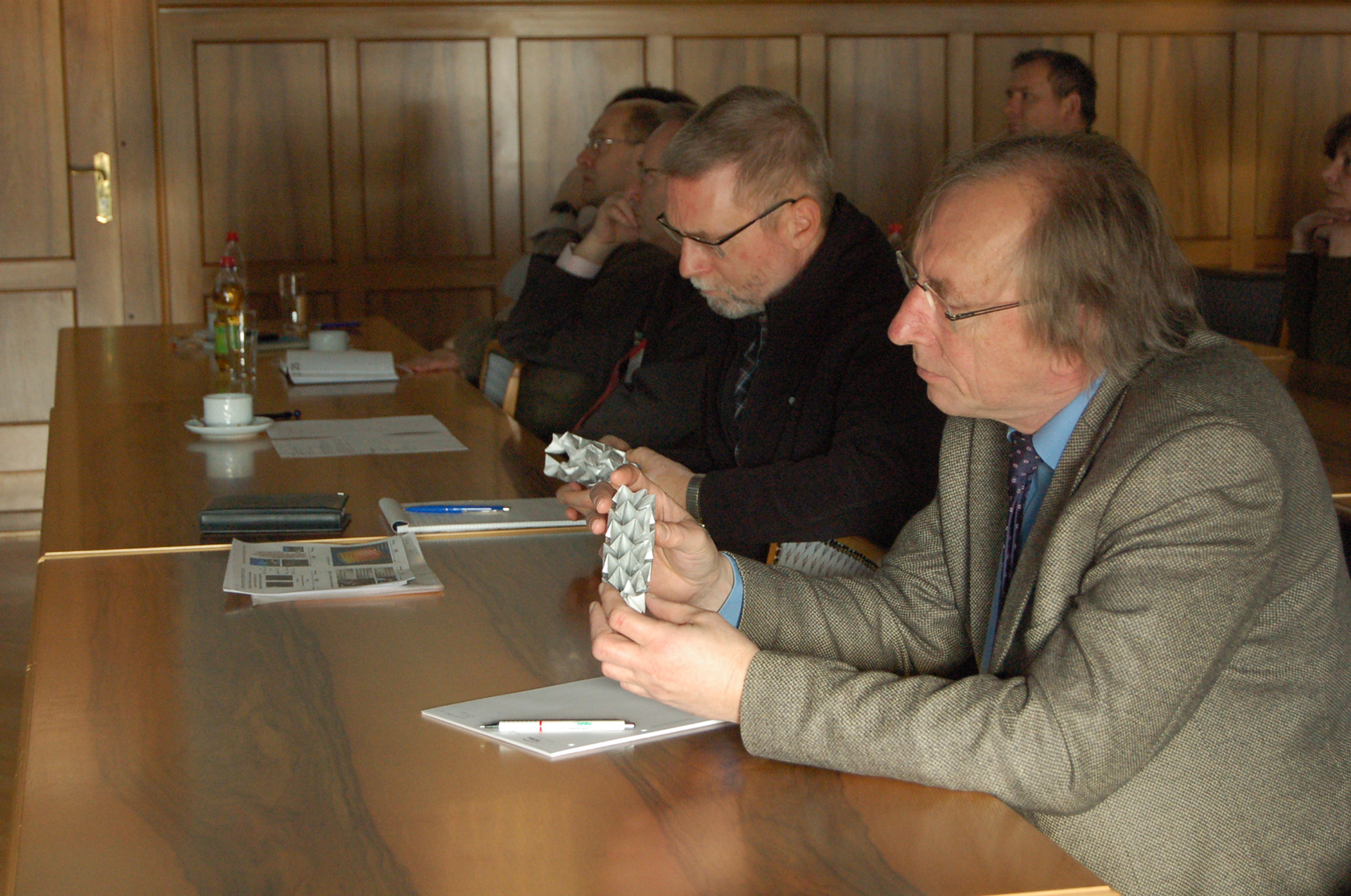 Participants of the ISC Fraunhofer Institute in Würzburg who examine Kristina Wißling's origami folding structures during her presentation.