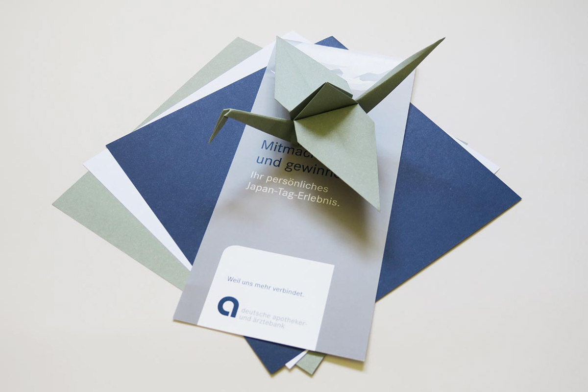 Folded origami crane made from specially produced origami paper in the company's corporate identity.
