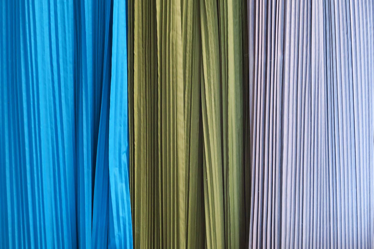 Blue, green and grey synthetic textile machine pleated using special machines and heat.