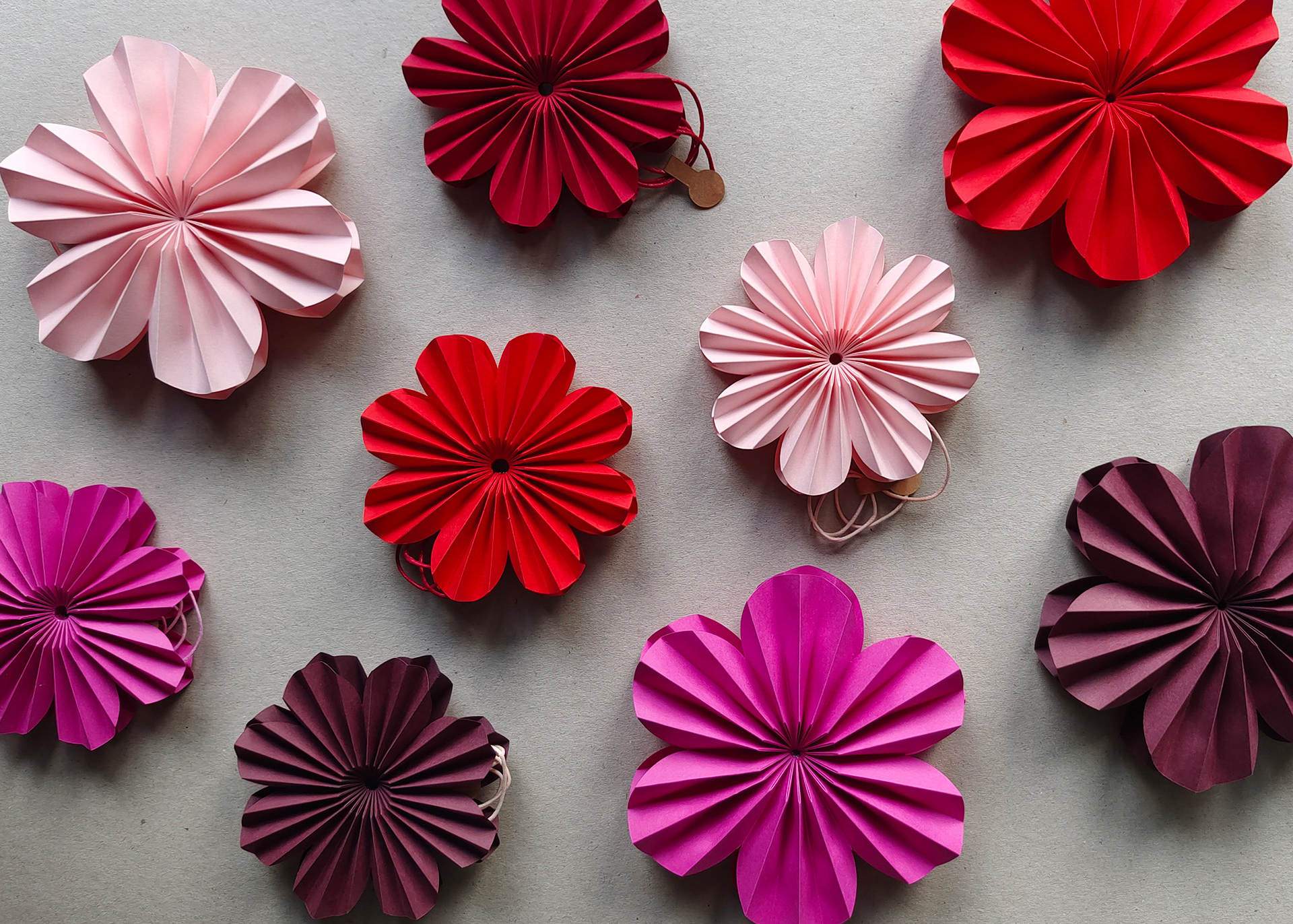 Pleated origami Flowers in different sizes and shades of red. Handmade by designer Kristina Wissling.