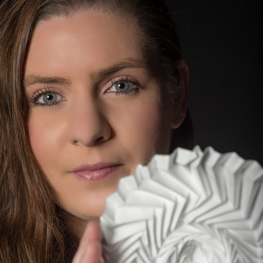 Portrait of designer Kristina Wißling with a white folding structure in her hands.