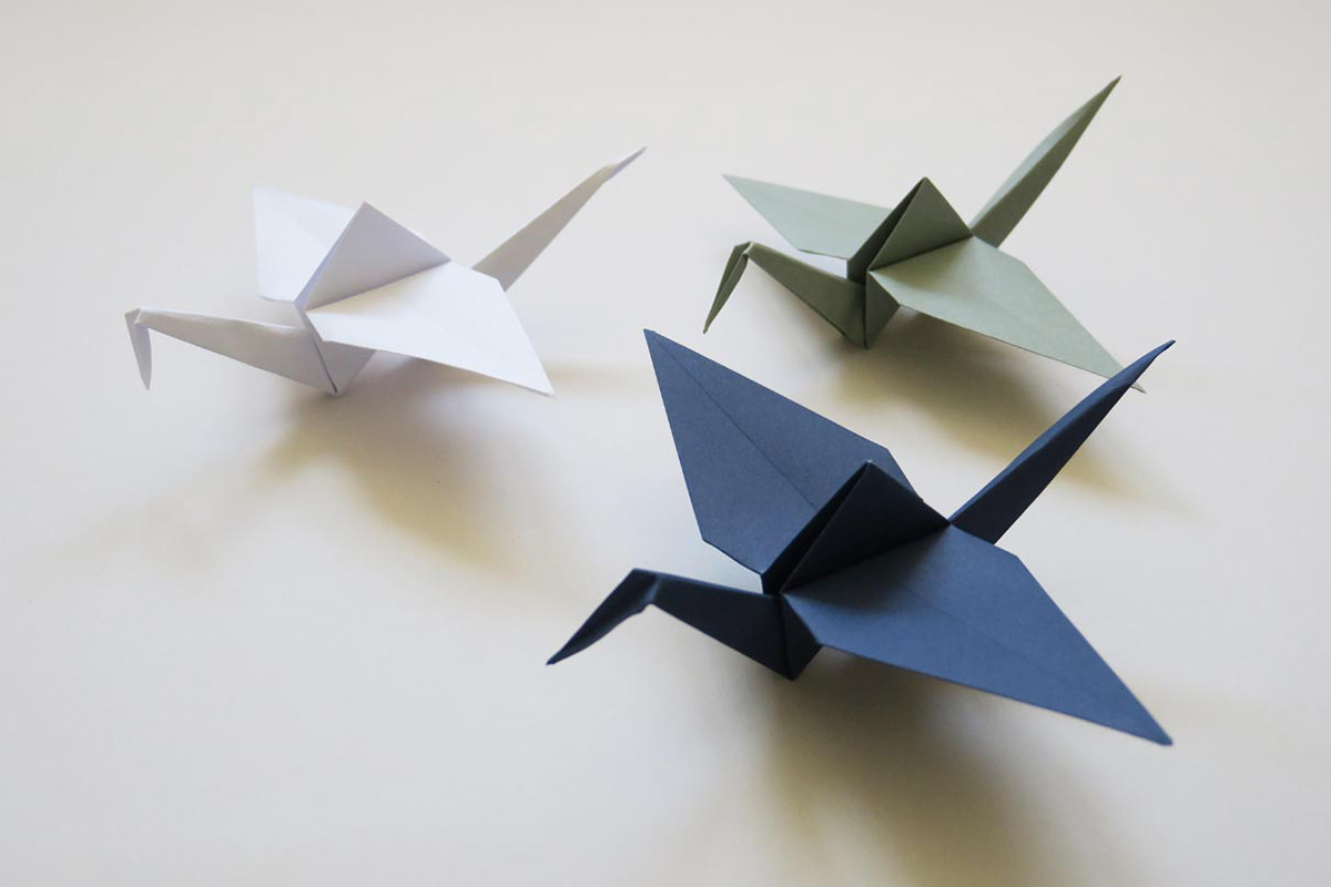 Folded cranes in three different colors made from specially produced origami paper in the customer's corporate identity colors.