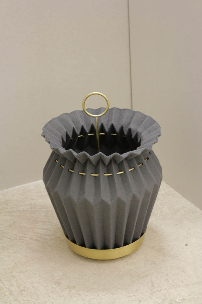 Student work of a container made of pleated felt with a metal holder as a storage option in the entrance area.