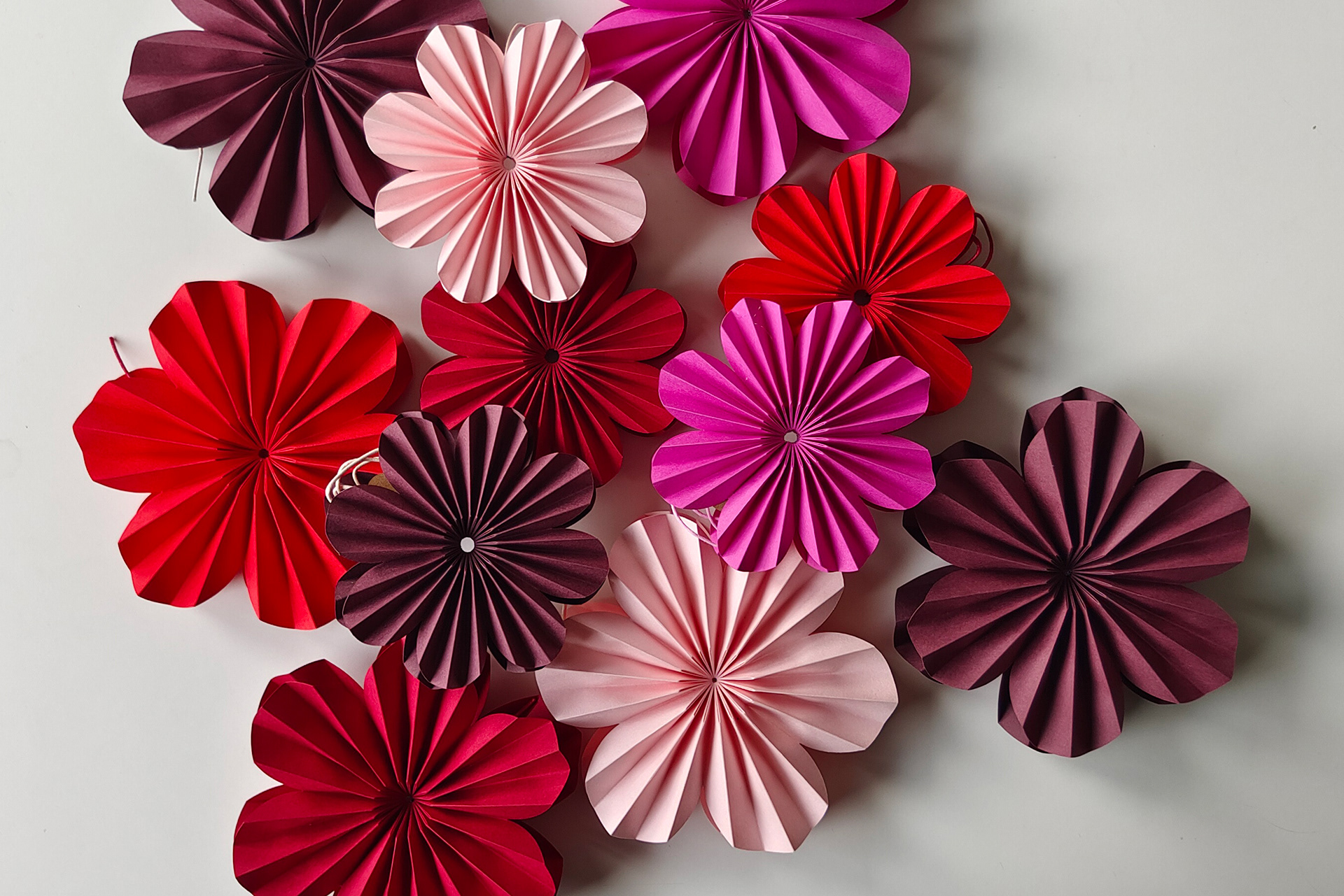 Lots of pleated paper flowers in different shades of red and different sizes. use as a pendant or for decoration on your table.