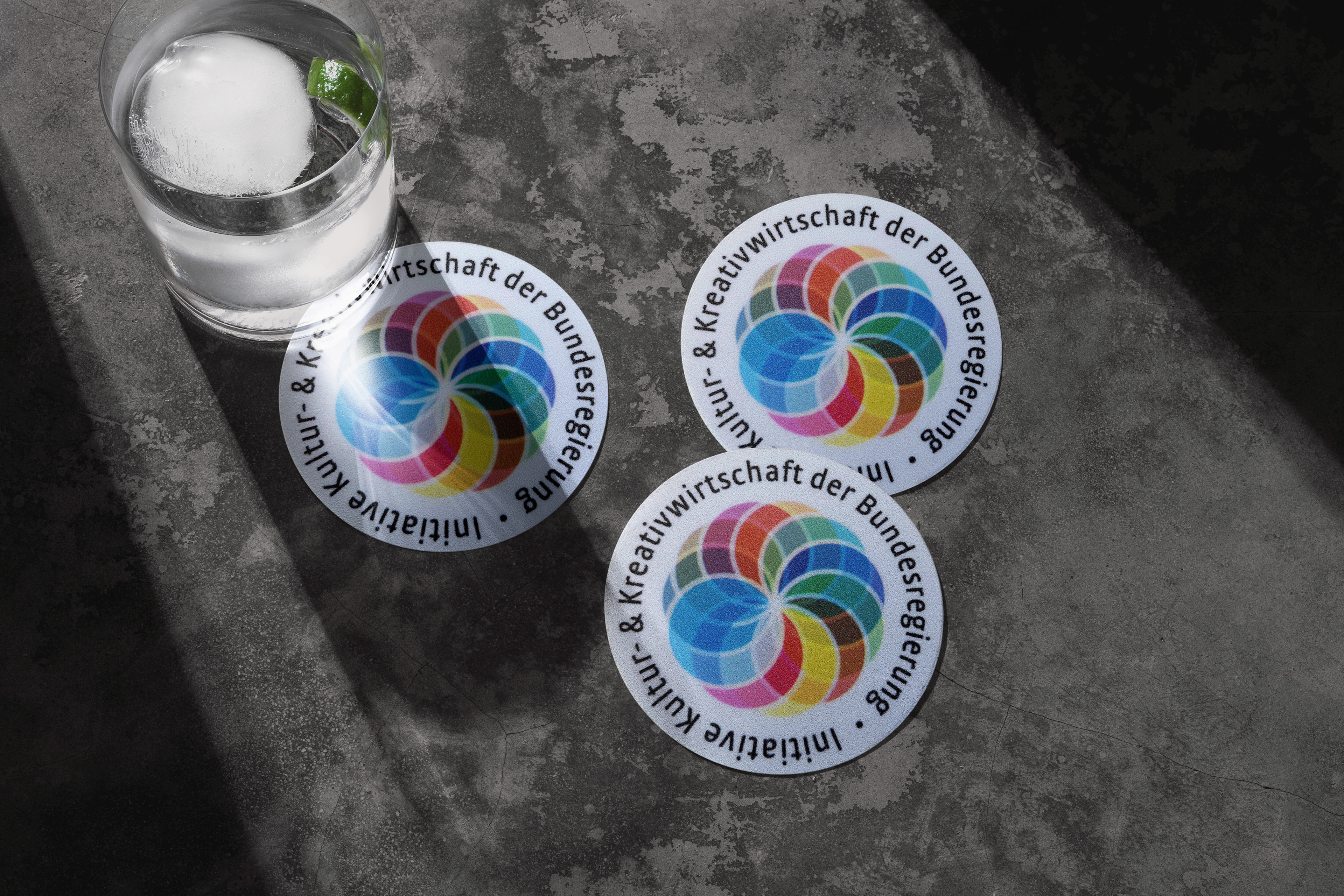 Glass coasters with the logo of the Federal Government’s Cultural and Creative Industries Initiative.