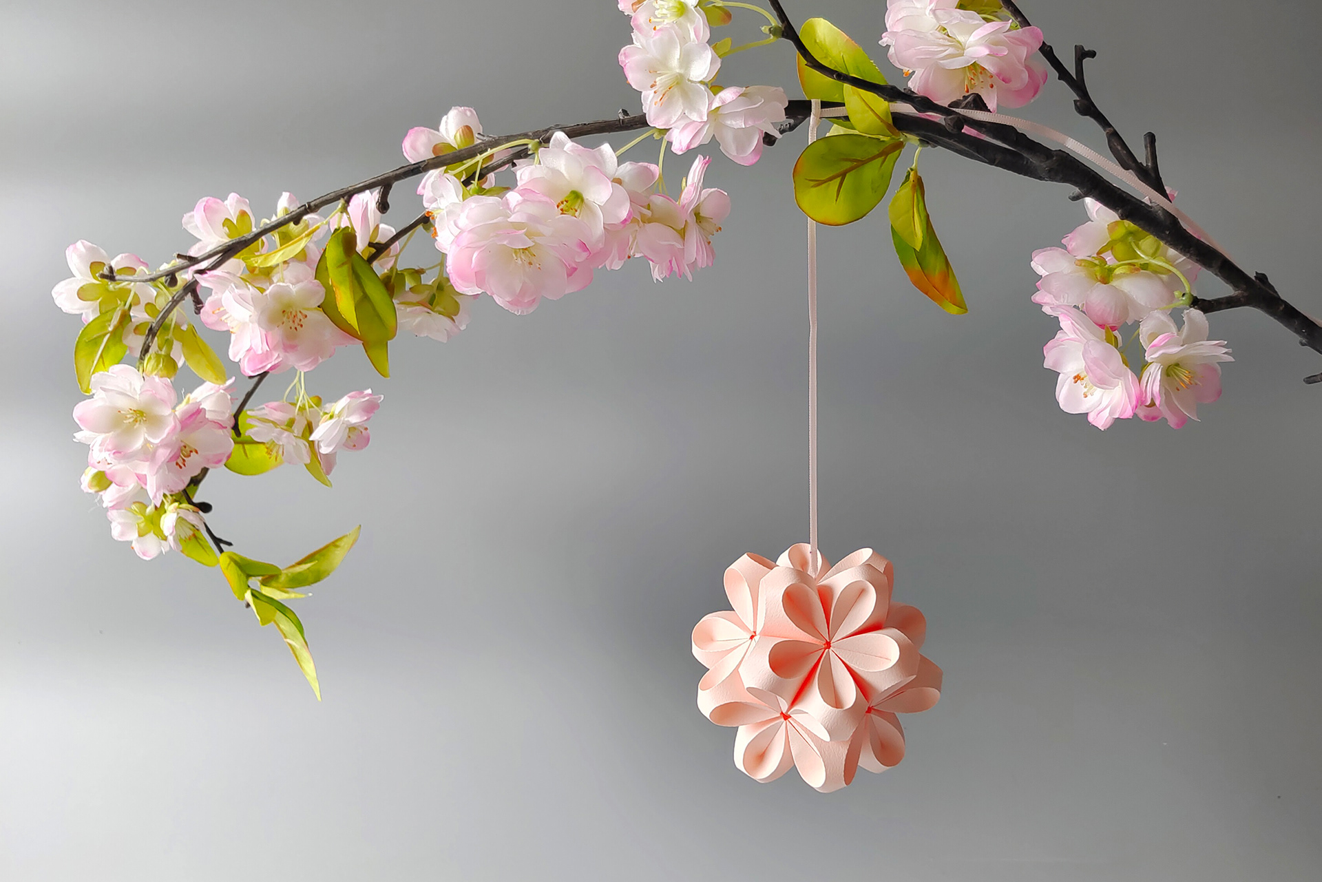 Origami paper flower handcrafted by Kristina Wissling and decorated with twigs and branches.