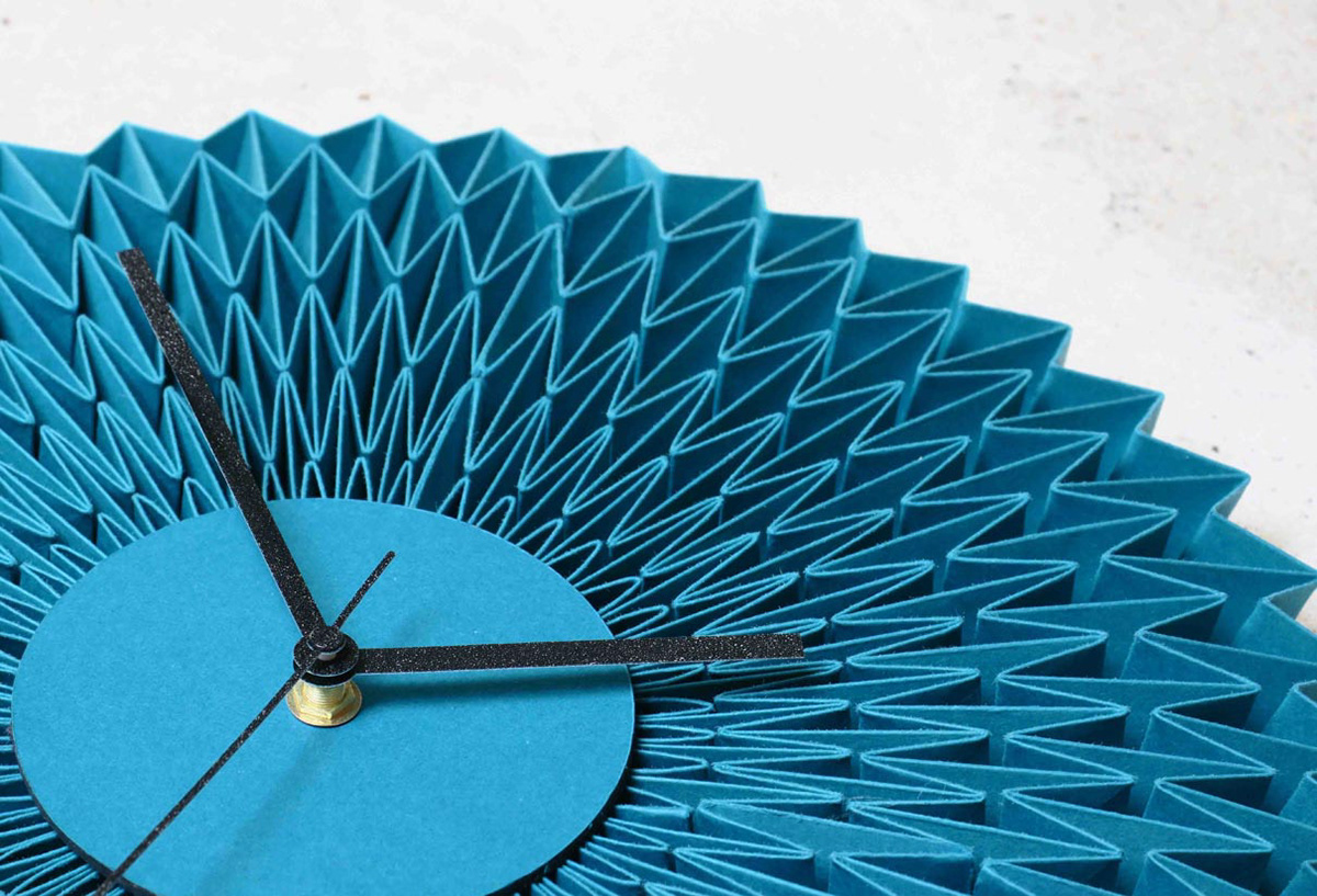 Turquoise paper wall clock designed and folded by designer Kristina Wissling for a trade fair stand.