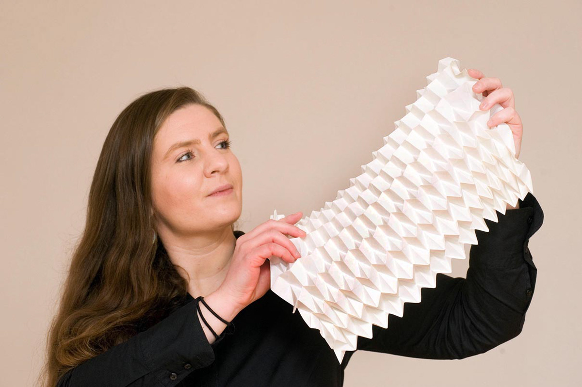 The designer Kristina Wißling with an origami folding structure made of synthetic paper.