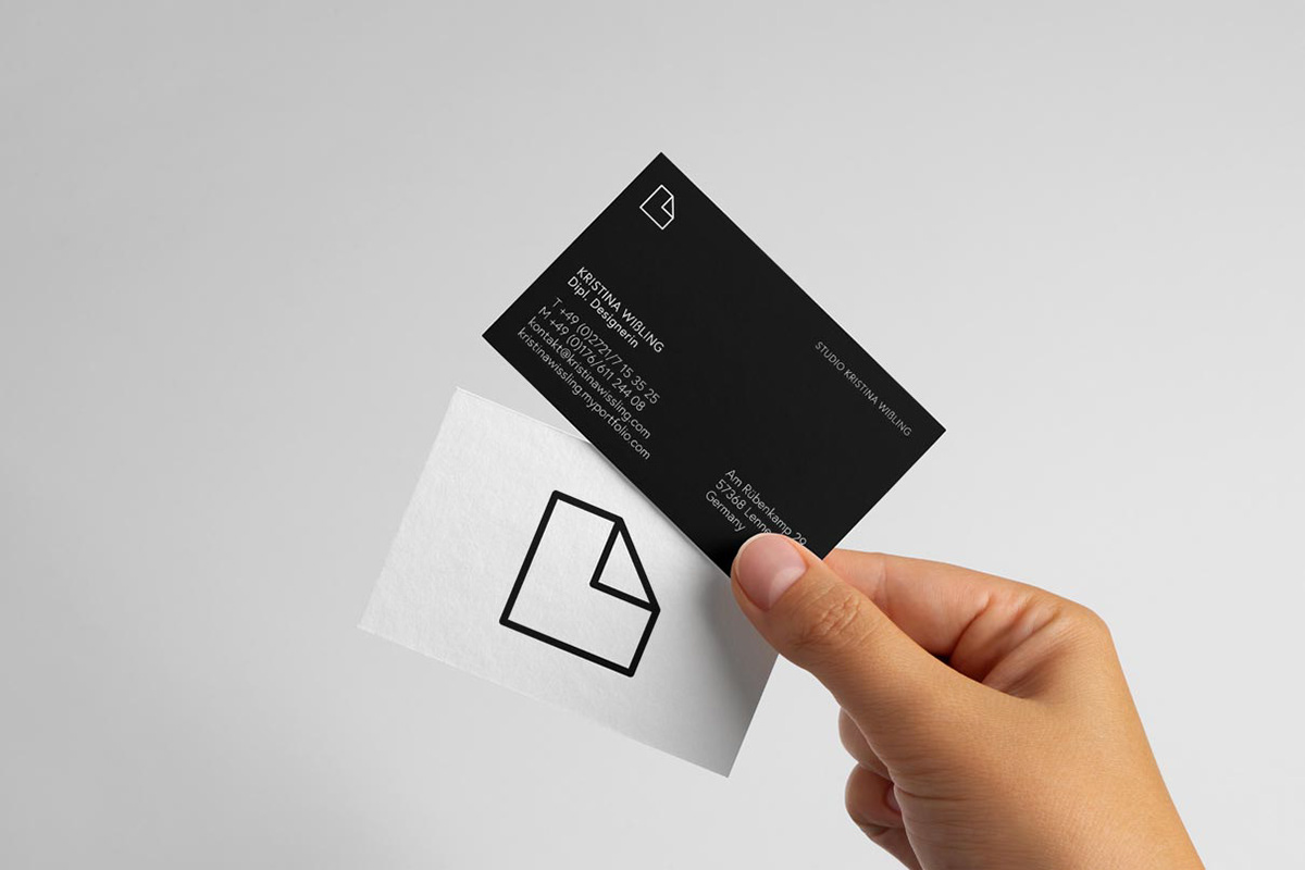 A hand holding two business cards from Designer Kristina Wissling.