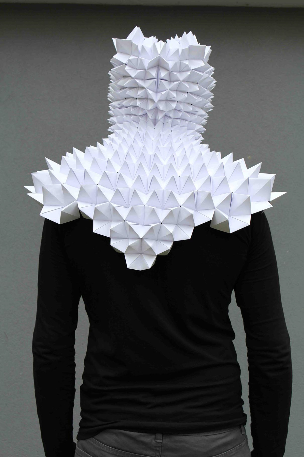Student with a cape made of modular paper folds. Individual origami folds were woven into a cloak