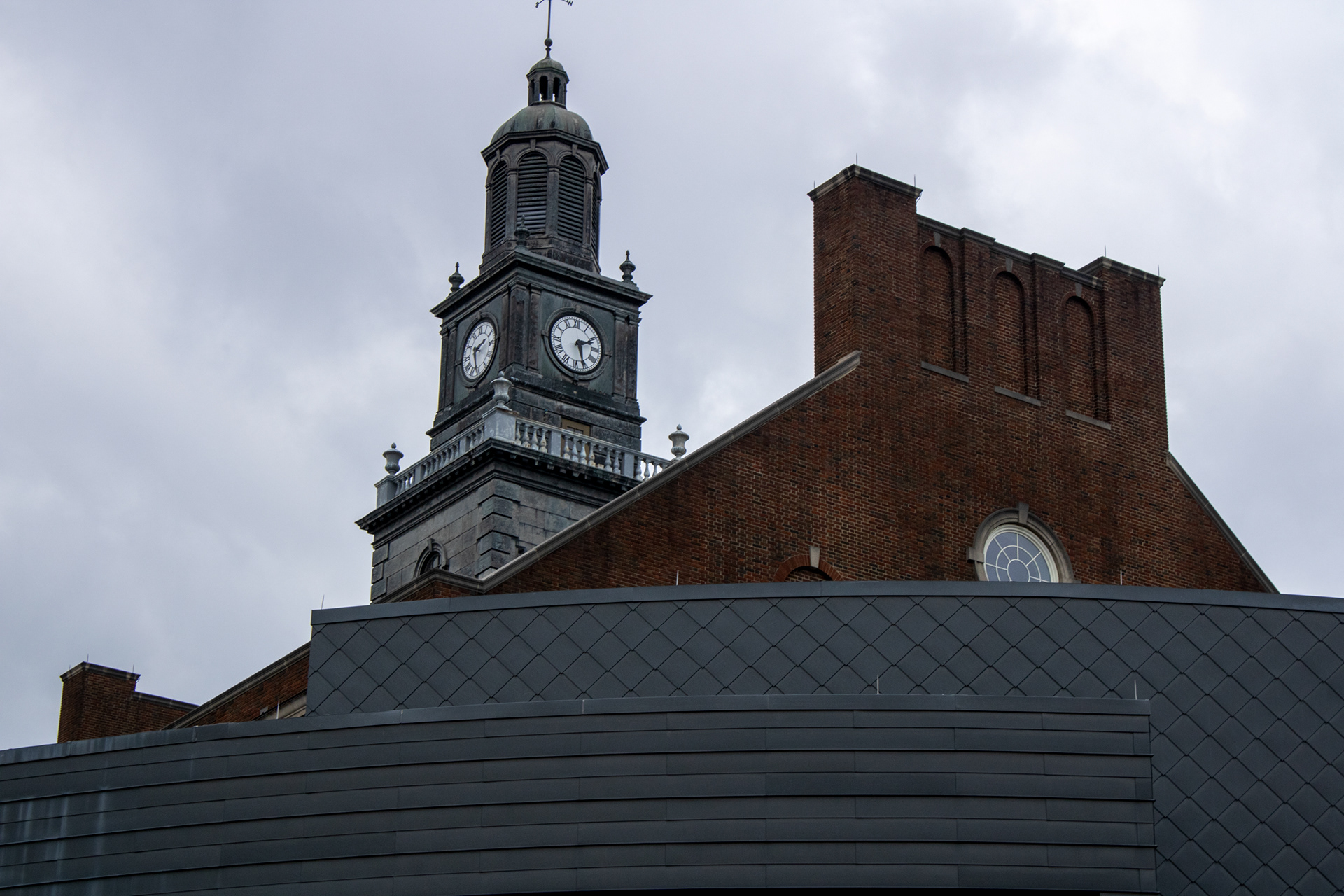 "Timekeeper"(2024), Photography 20''x30'', This photo captures the contrast between past and present — the old clock tower standing firm behind modern architecture. It reflects how time layers history and progress within the same frame.