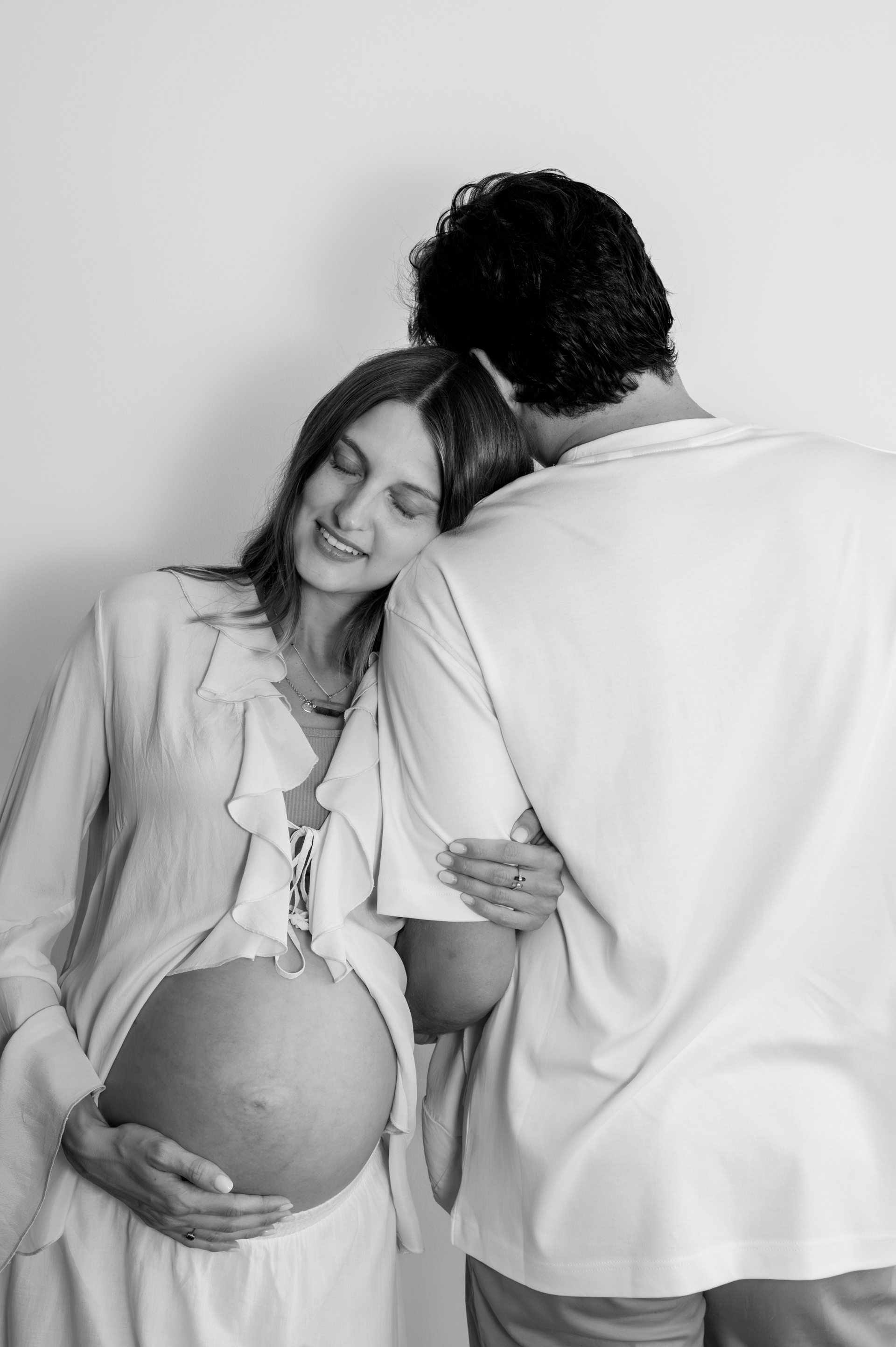 	Pregnant woman resting her head on her partner's shoulder, black and white