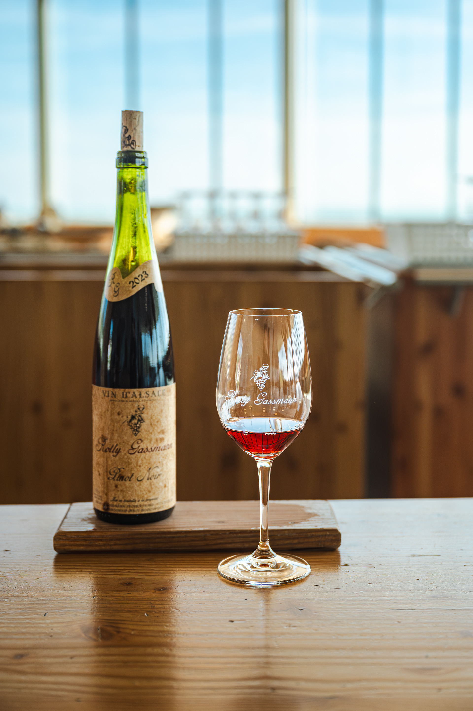 Rolly Gassmann Pinot Noir with a glass of red wine in the tasting room