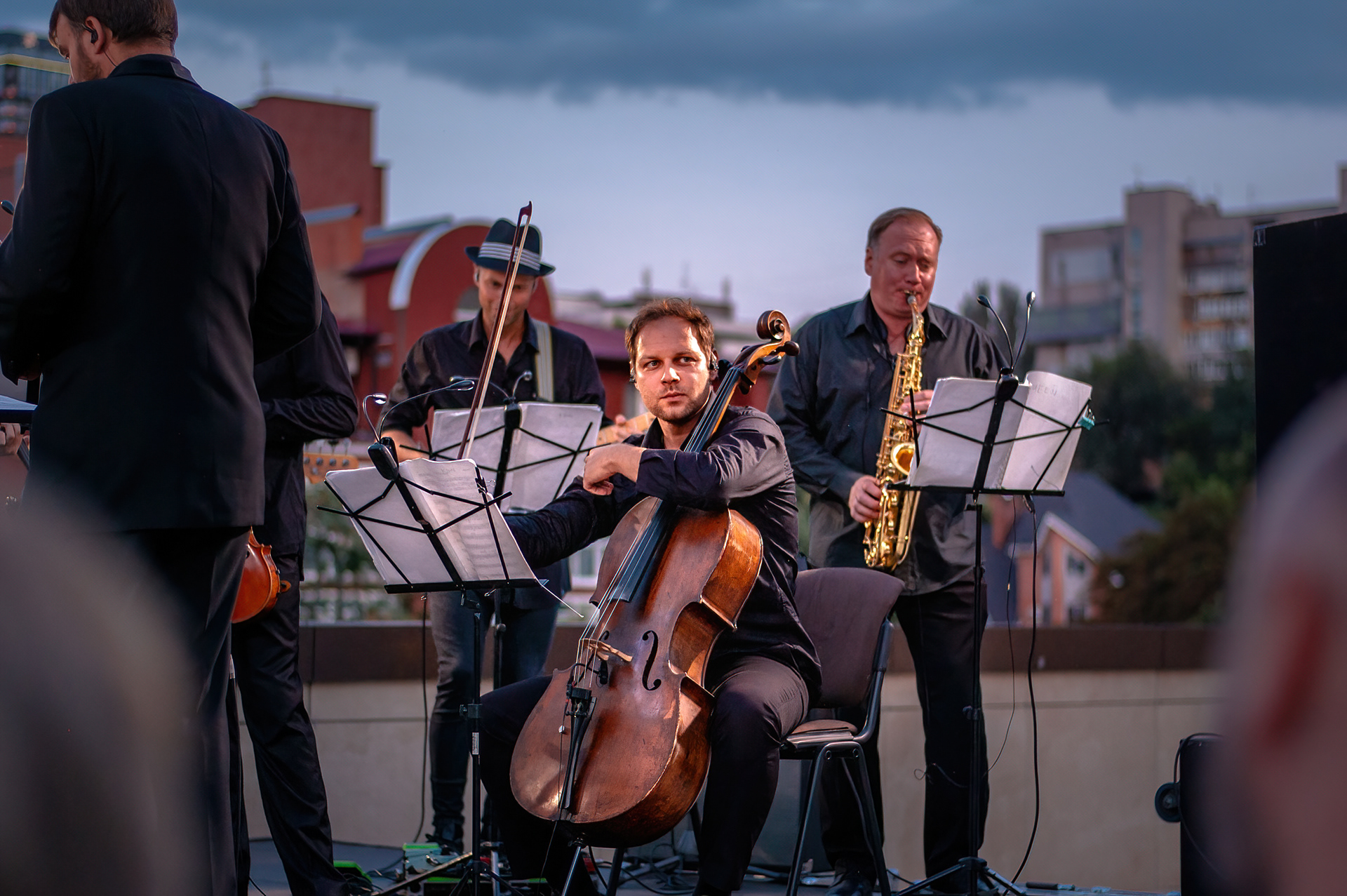Cellist and saxophonist performing with the orchestra at dusk