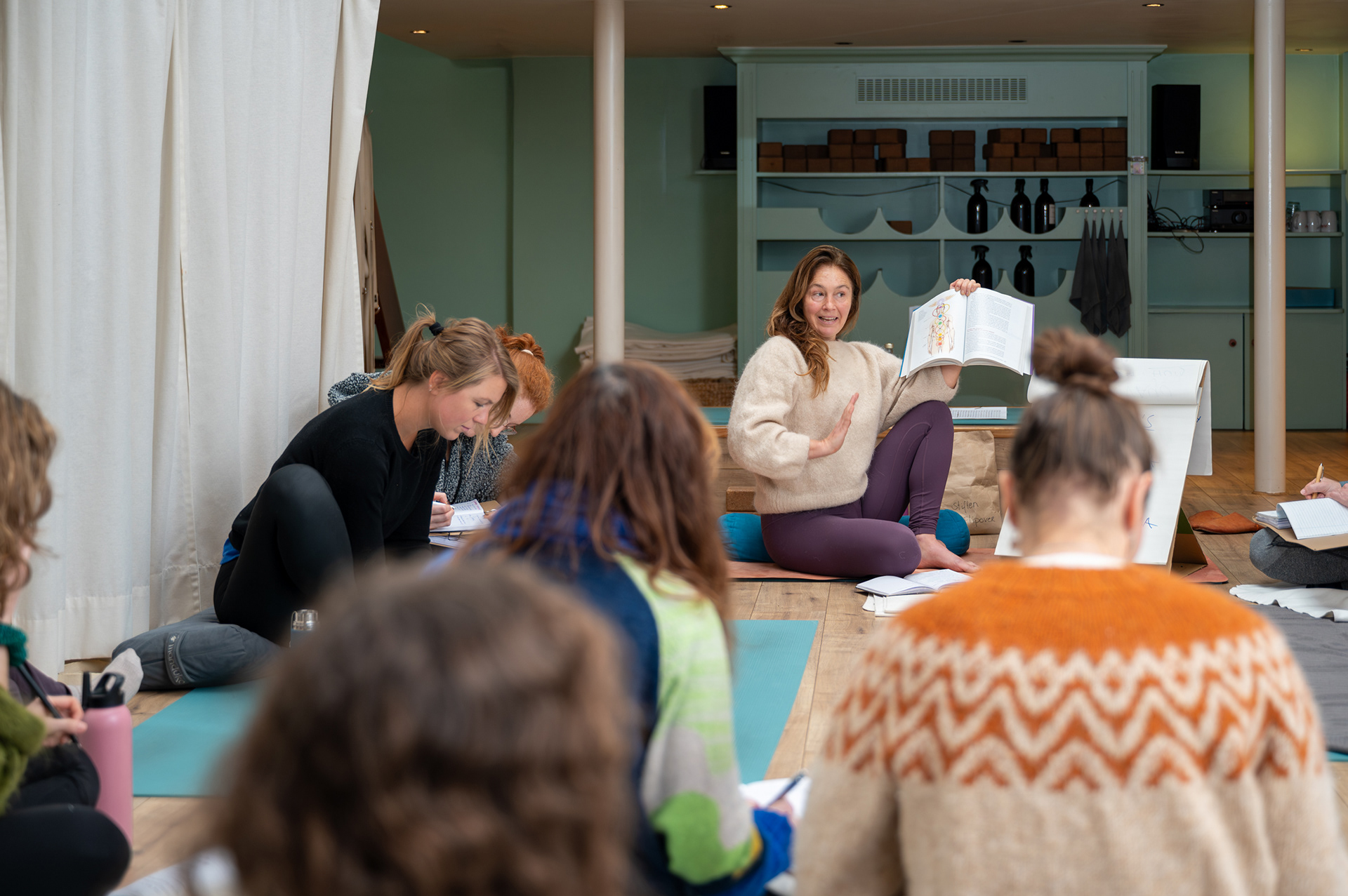 Yoga teacher showing an anatomy book during a workshop as part of teacher training