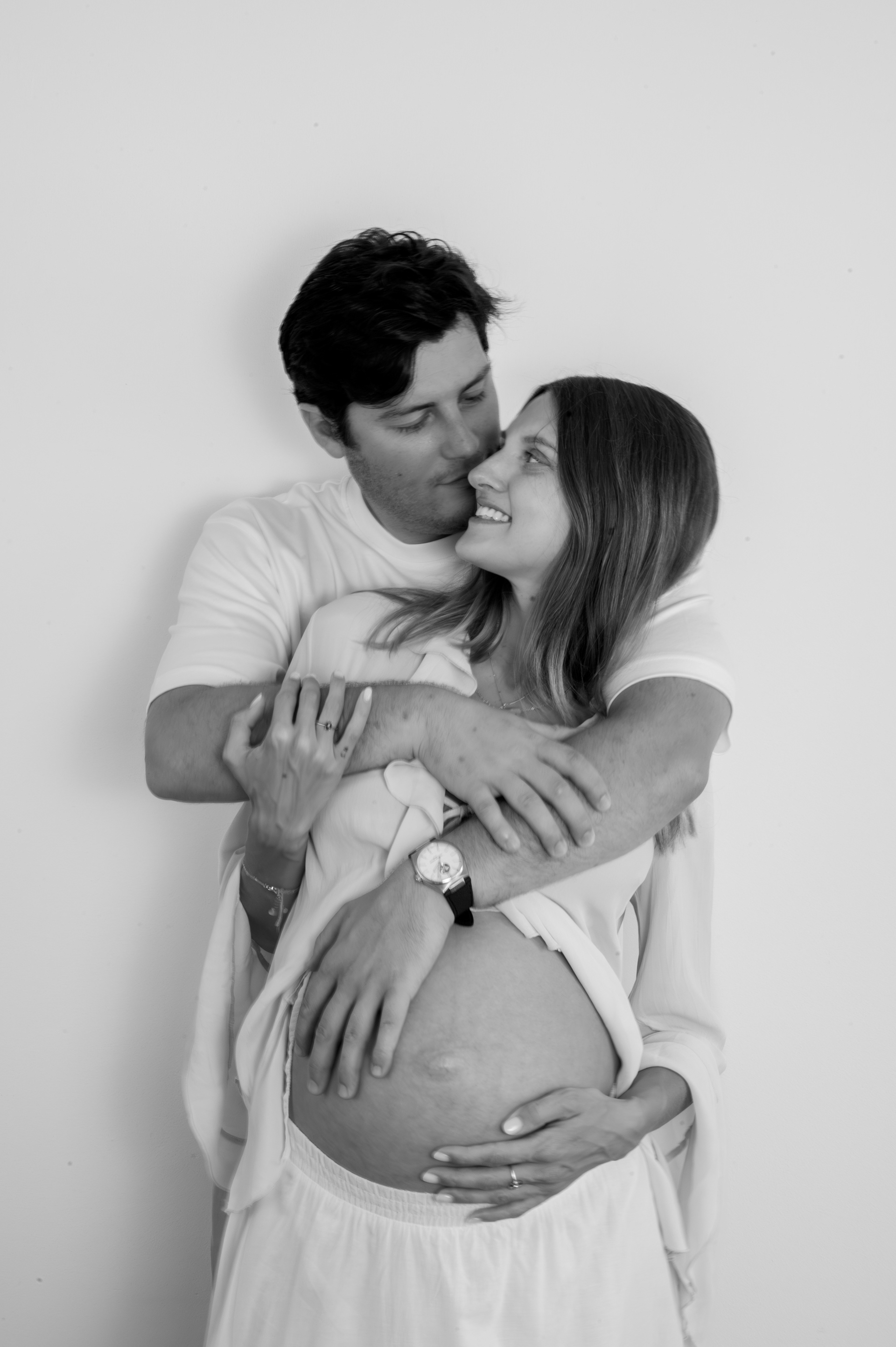 Couple embracing and smiling during a black and white maternity session