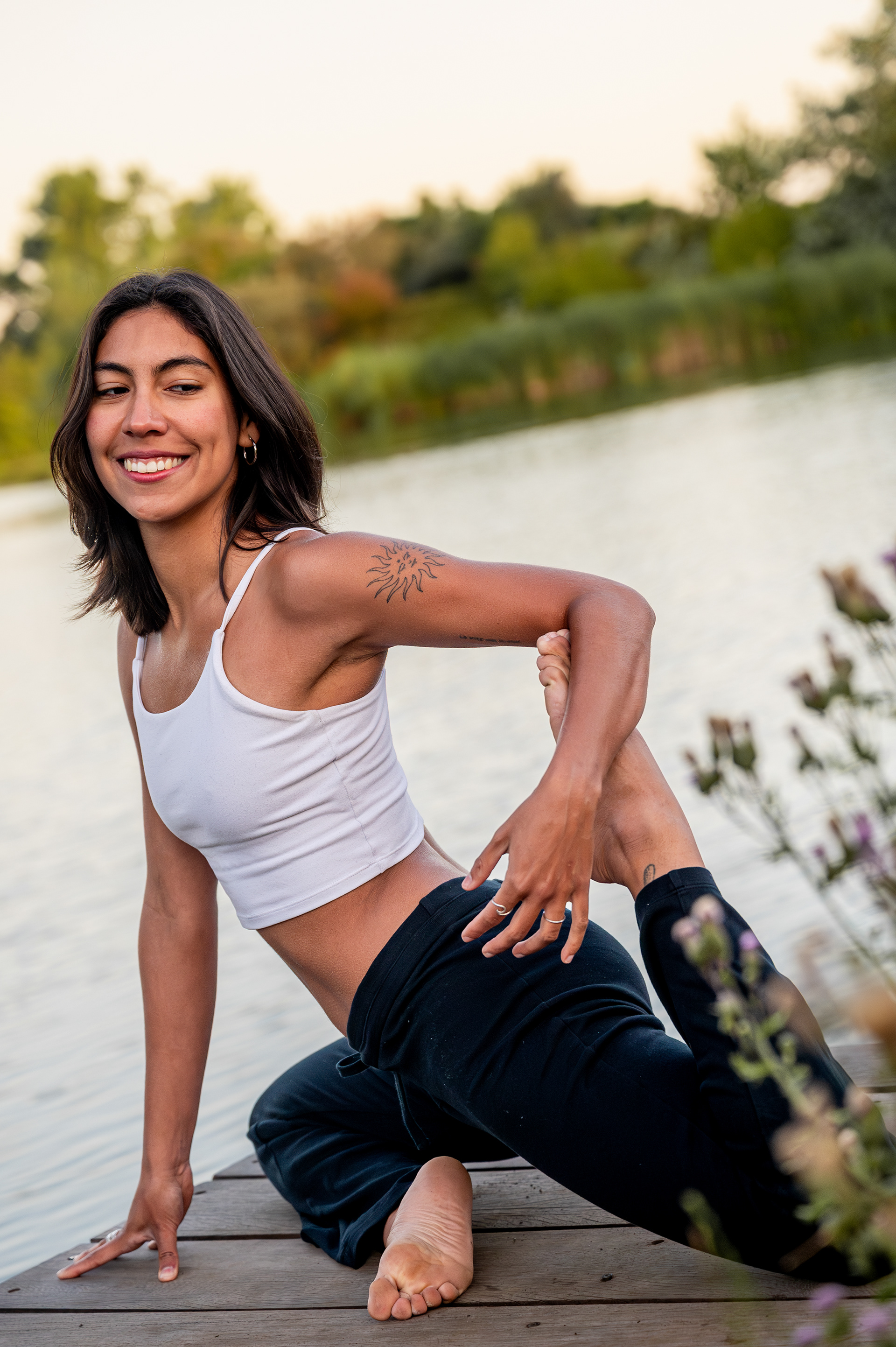 Smiling yoga teacher in a seated twist by the water