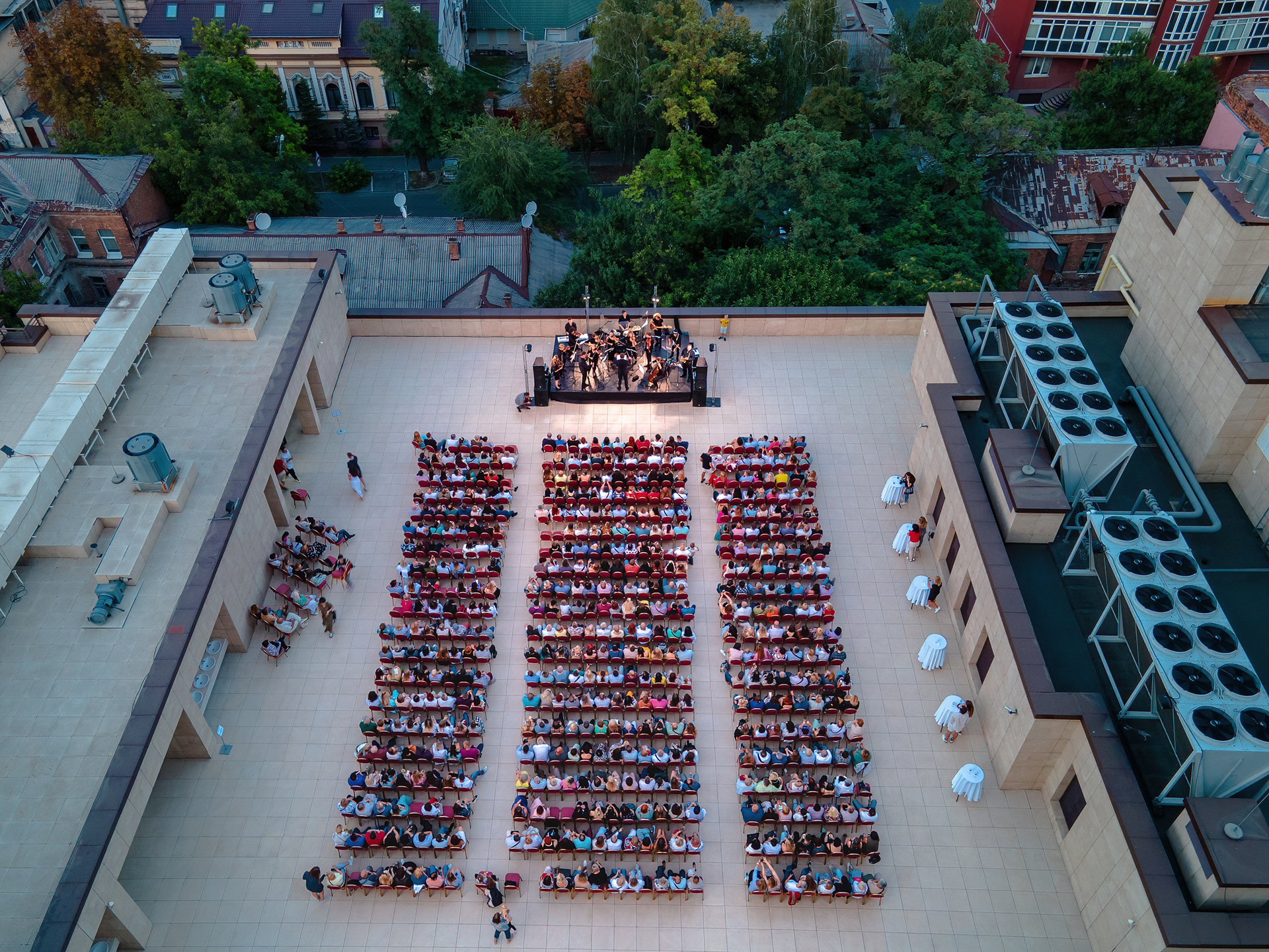 Top-down drone shot of the audience and orchestra at a rooftop concert