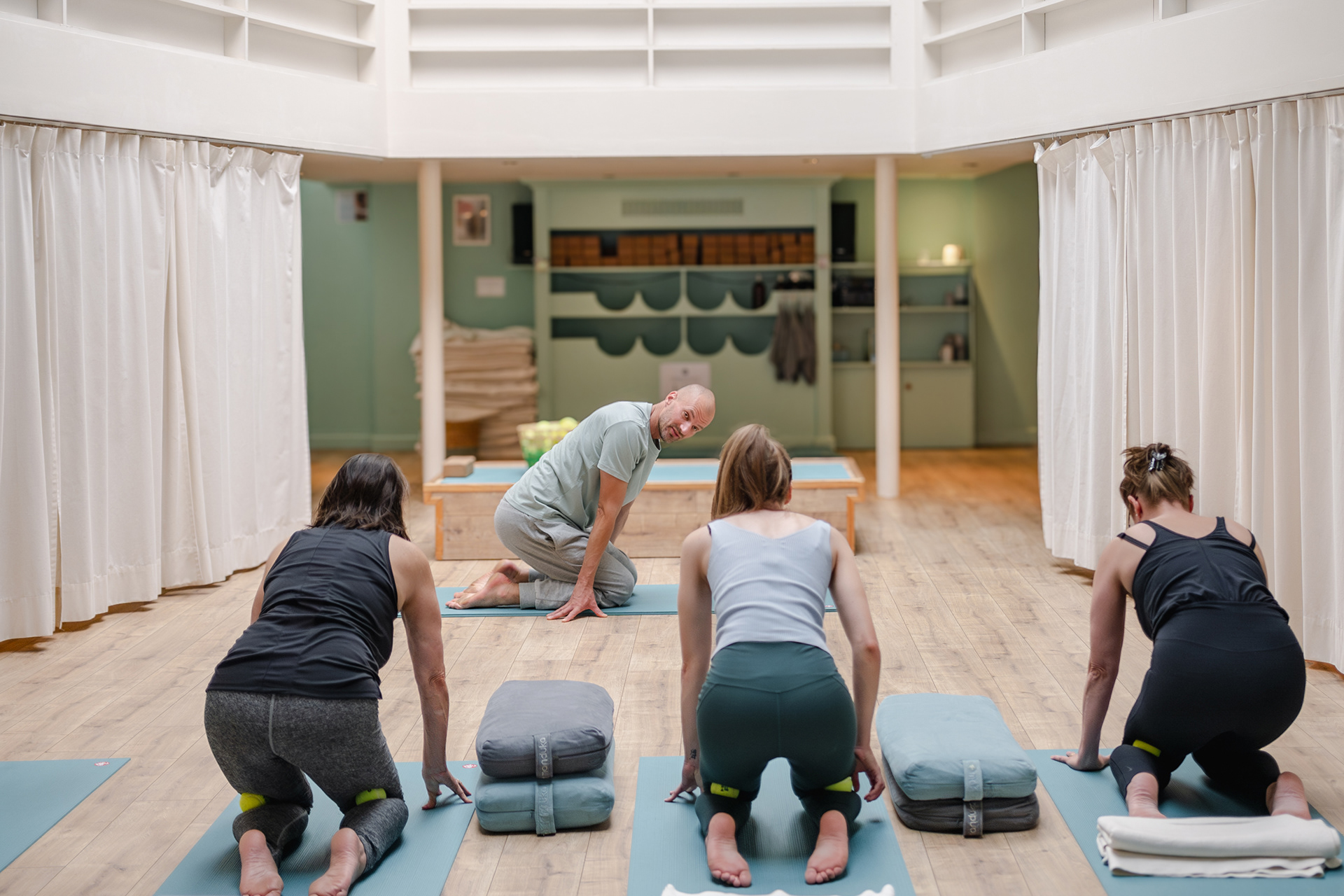 Alexander De Waele guiding three students in a kneeling pose at Yoga On Call during a Roll & Release workshop