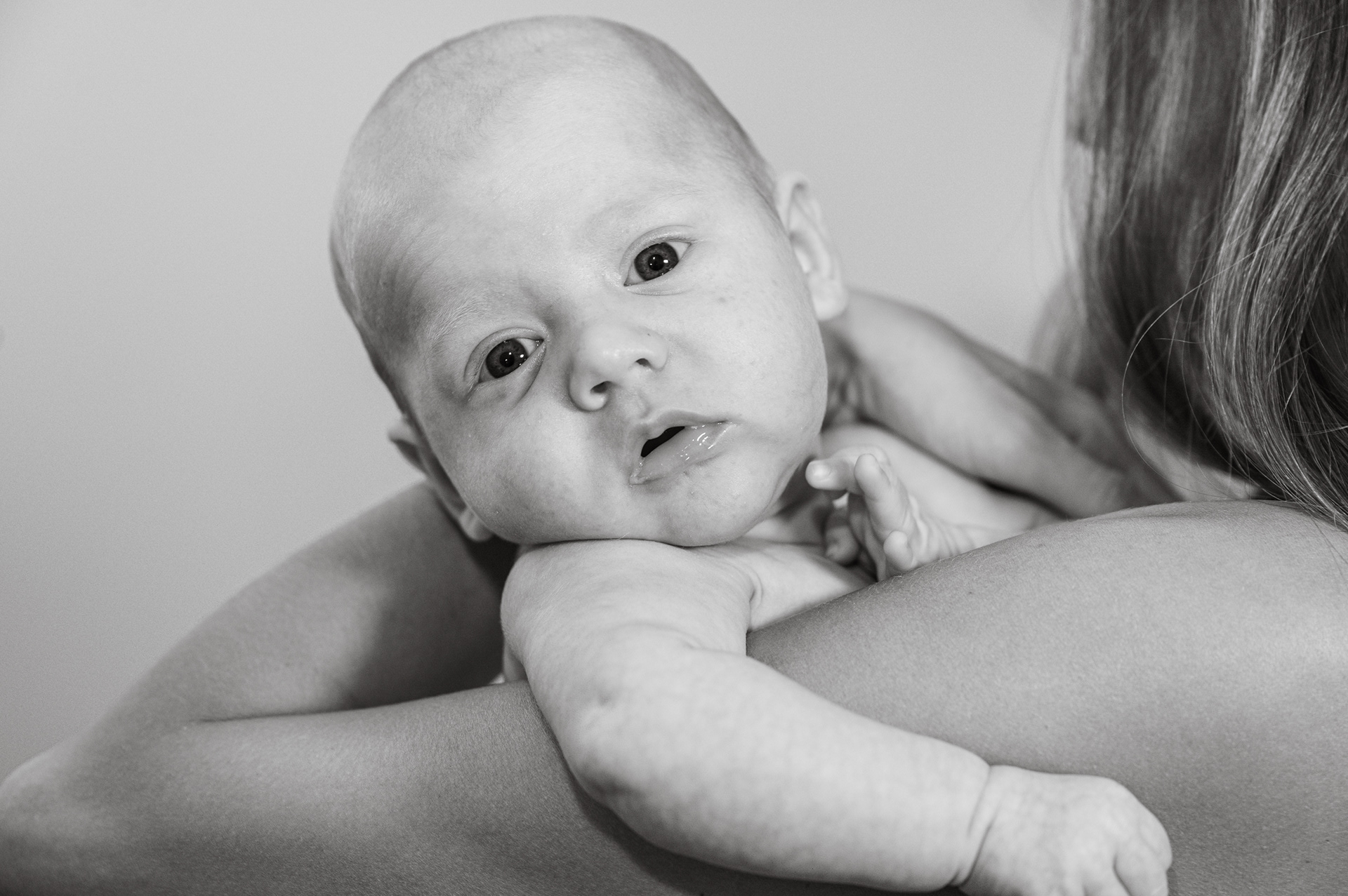 Black and white portrait of a baby resting on mom's shoulder