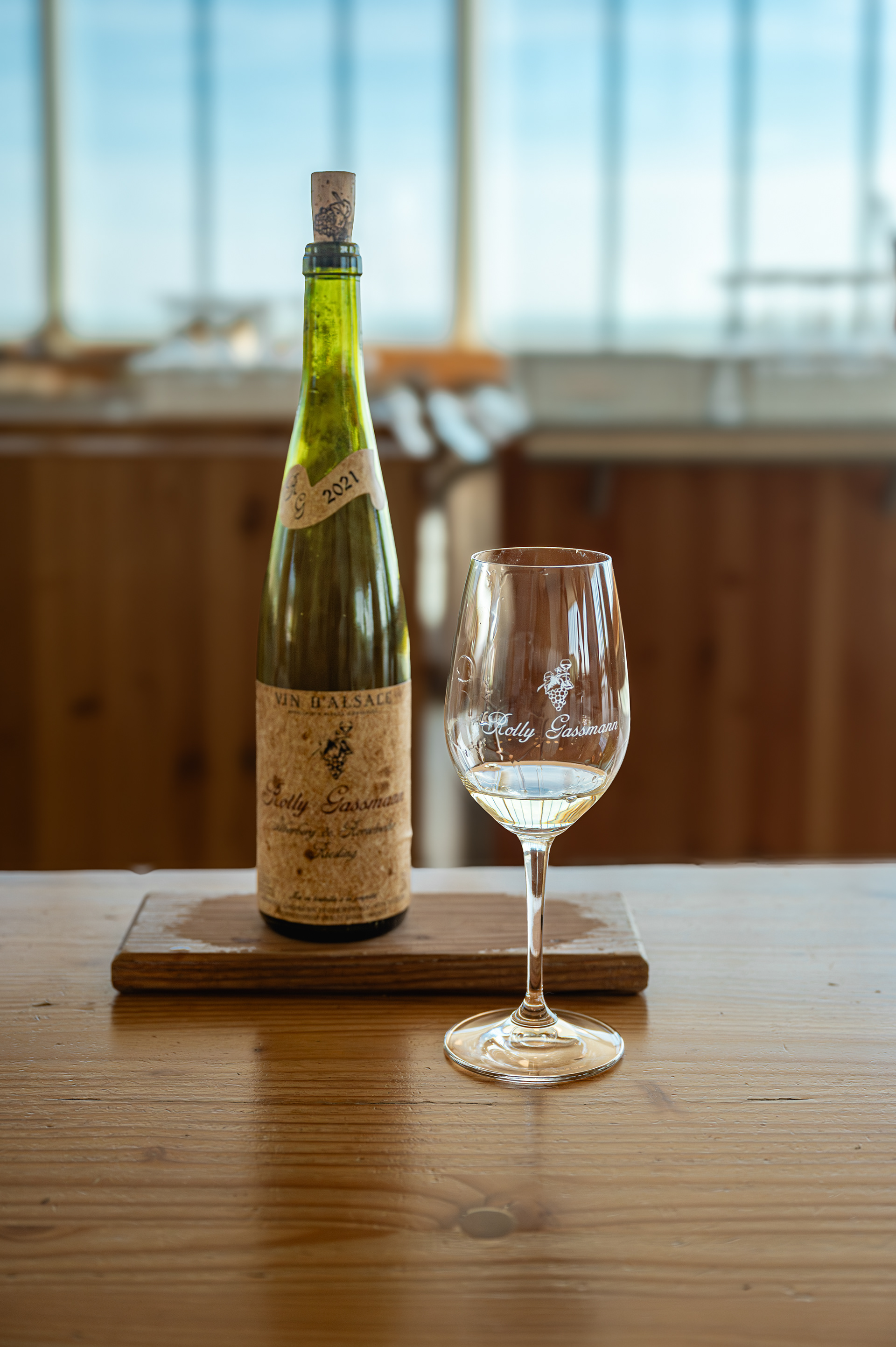 Bottle of Alsace white wine and a glass on a wooden table