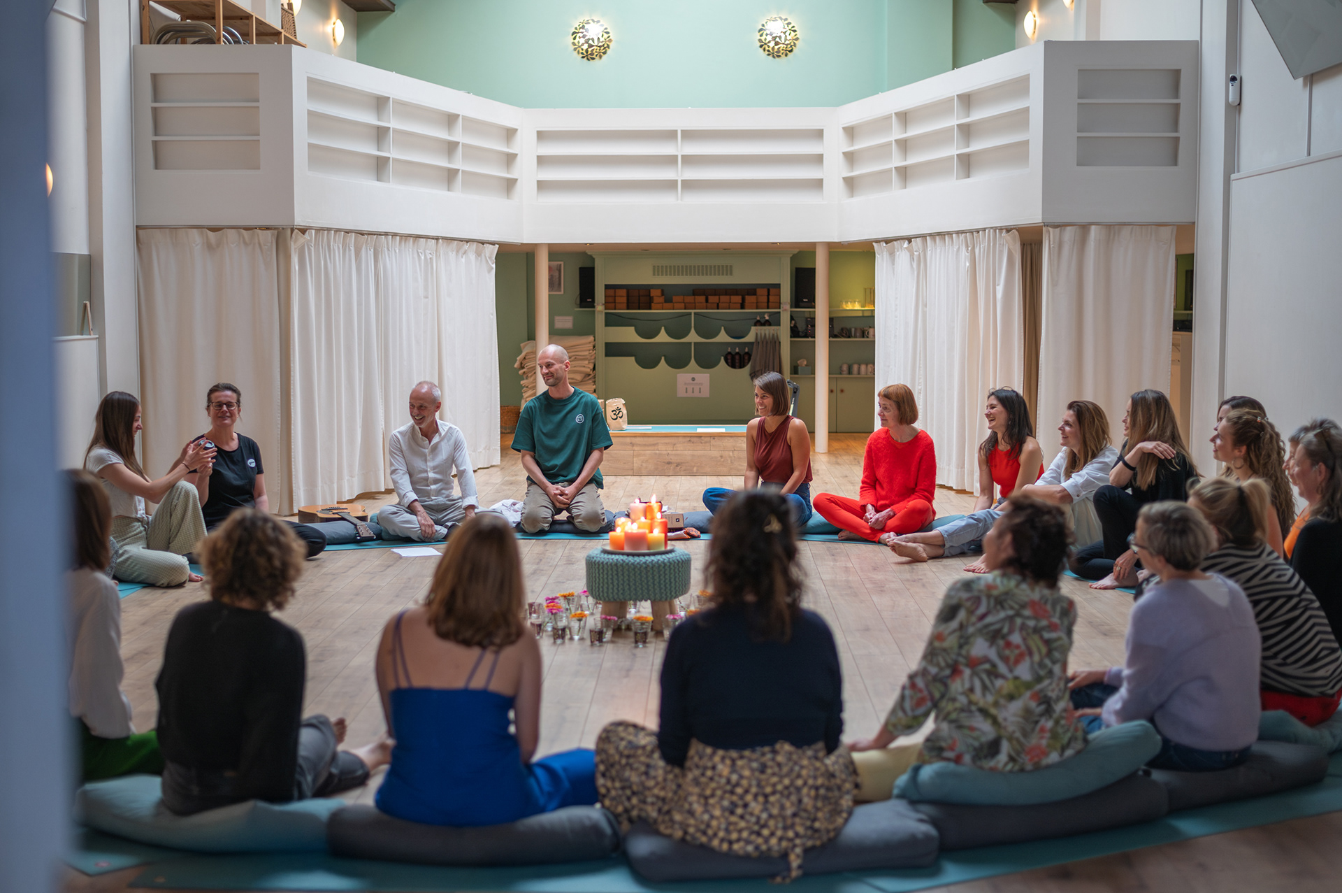 Yoga On Call community circle on meditation cushions around candles