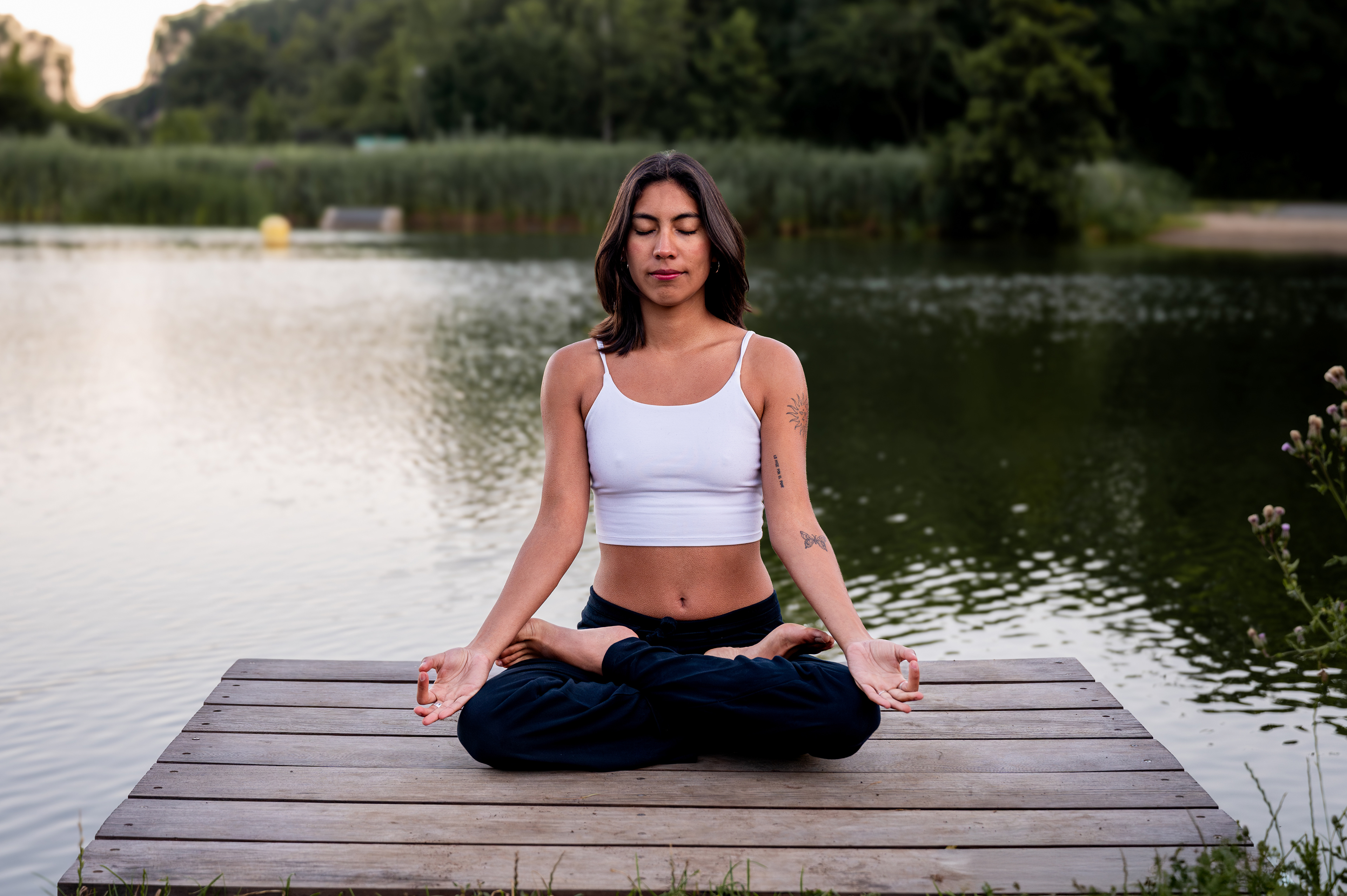 Yoga teacher Fernanda meditating in lotus pose on a jetty at Blaarmeersen, Ghent
