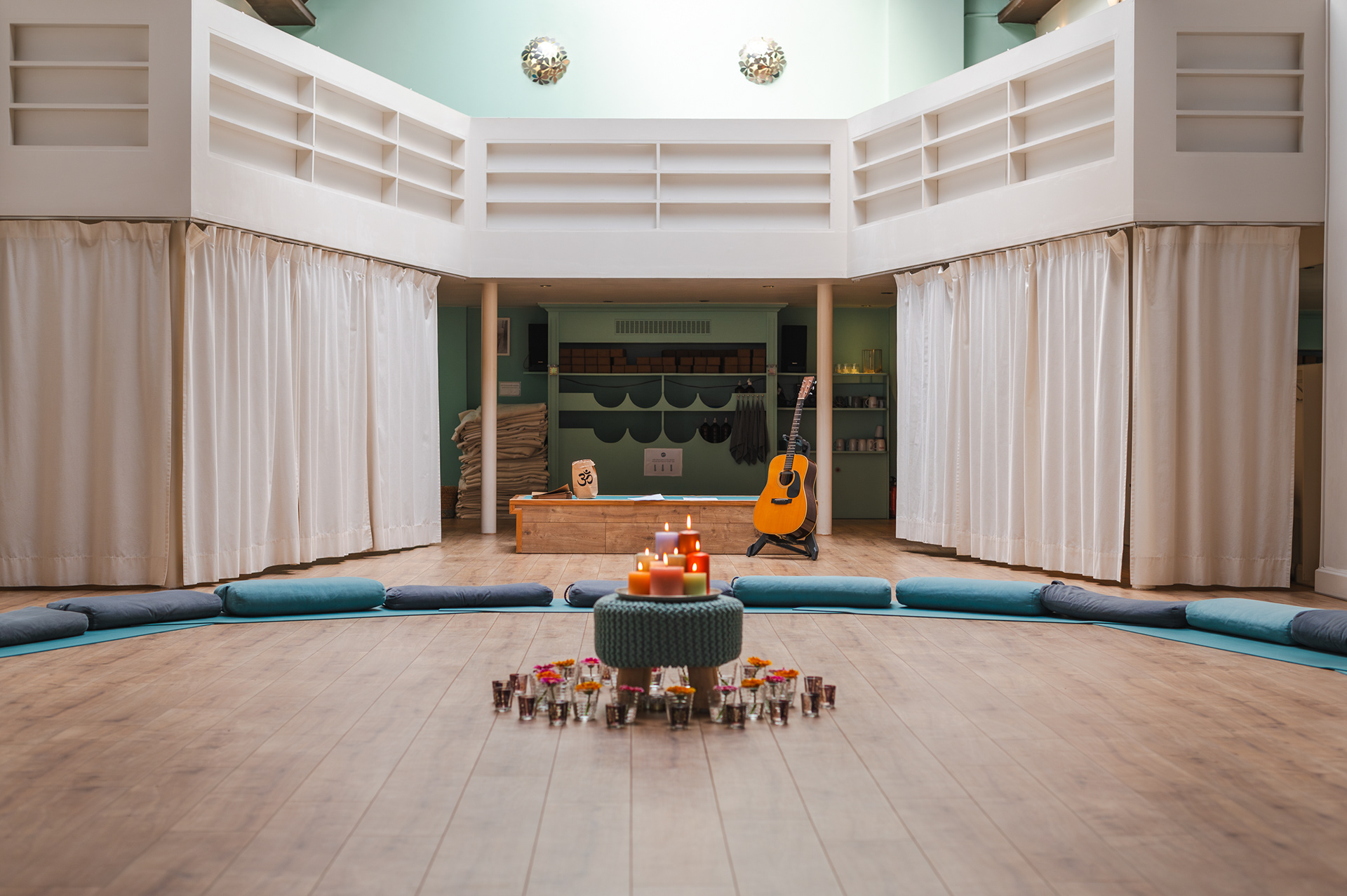 Studio set for a candlelit gathering with cushions in a circle and a guitar