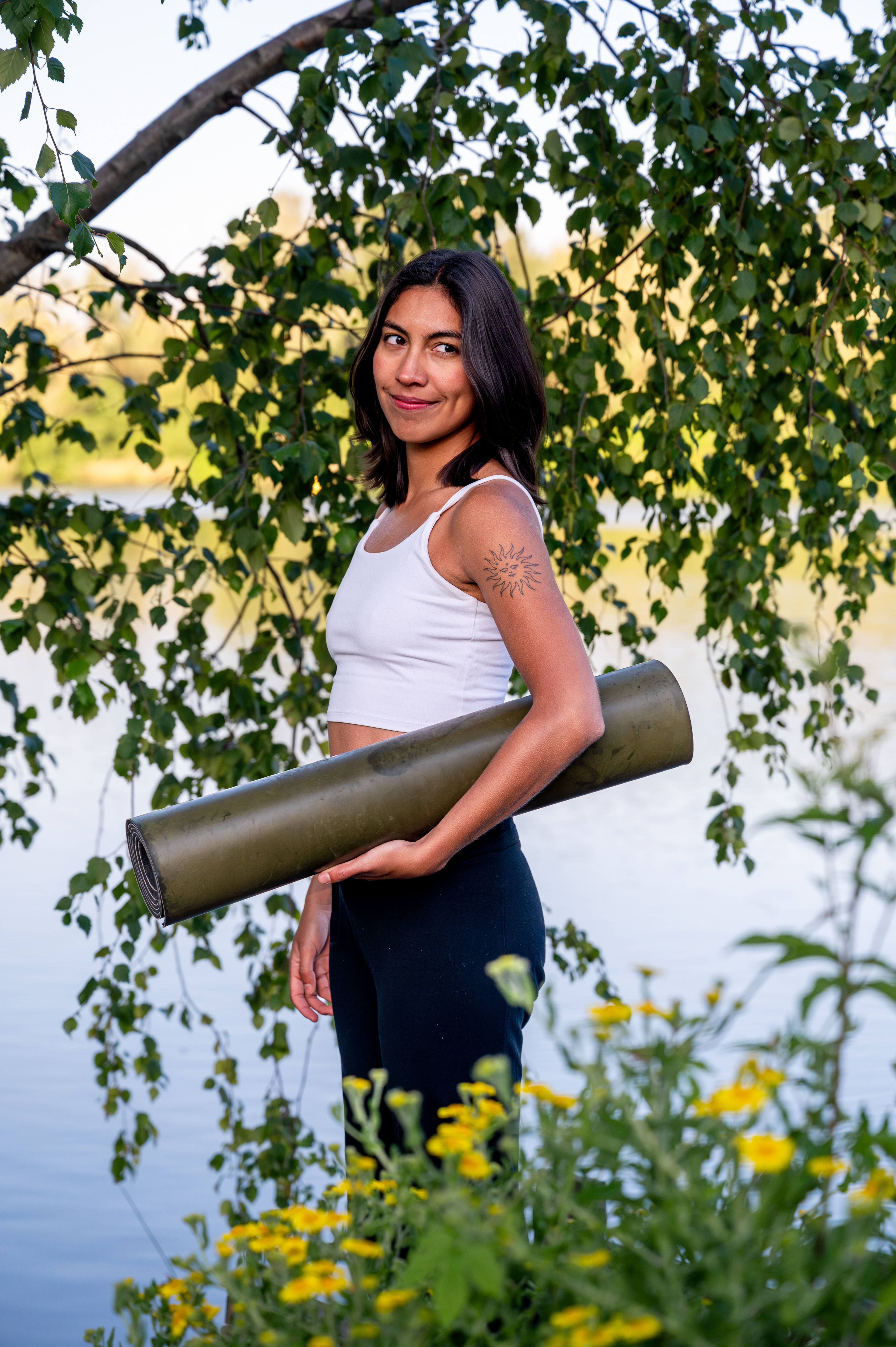 Portrait of a yoga teacher holding her mat under a birch tree