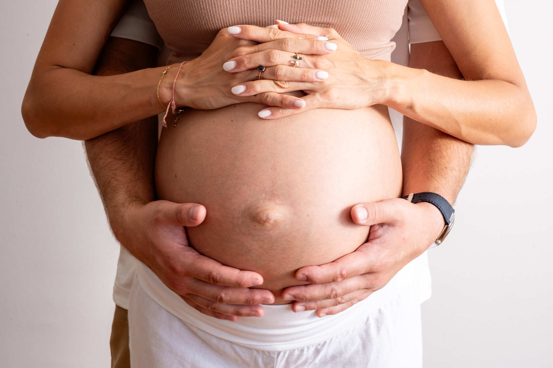 Couple's hands wrapped around a pregnant belly, maternity photography