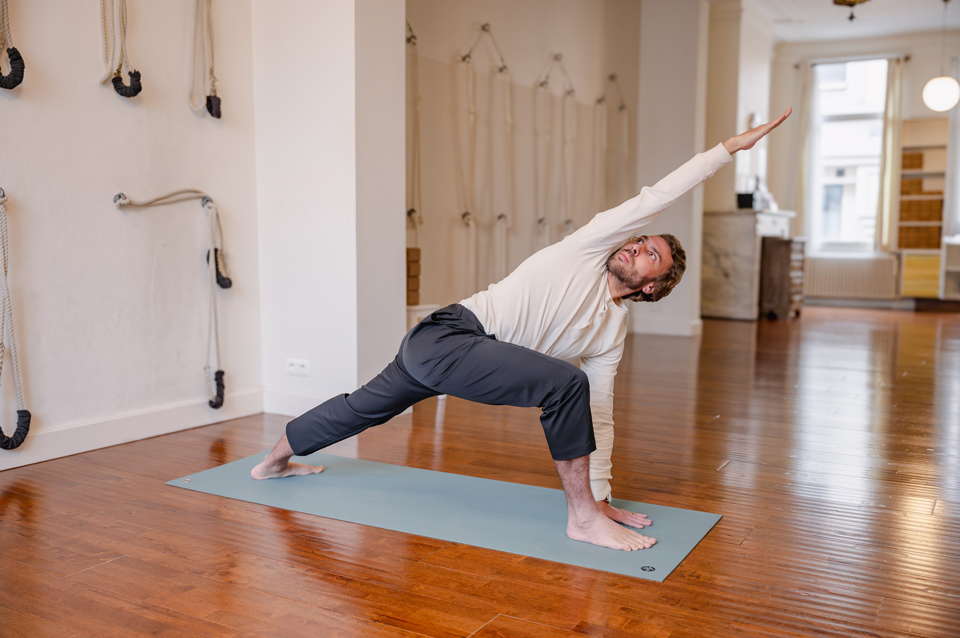Man in extended side angle pose in a bright yoga studio