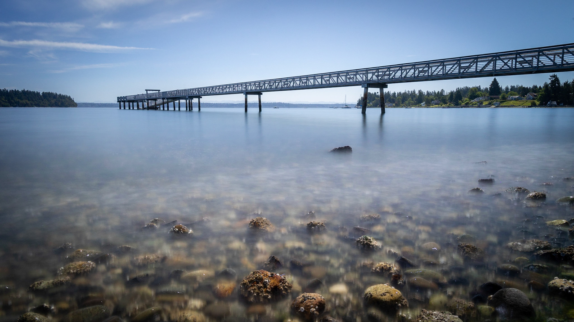 A fishing pier stretches well out into the bay at Harper, WA. This long exposure calms the excitement of the water.