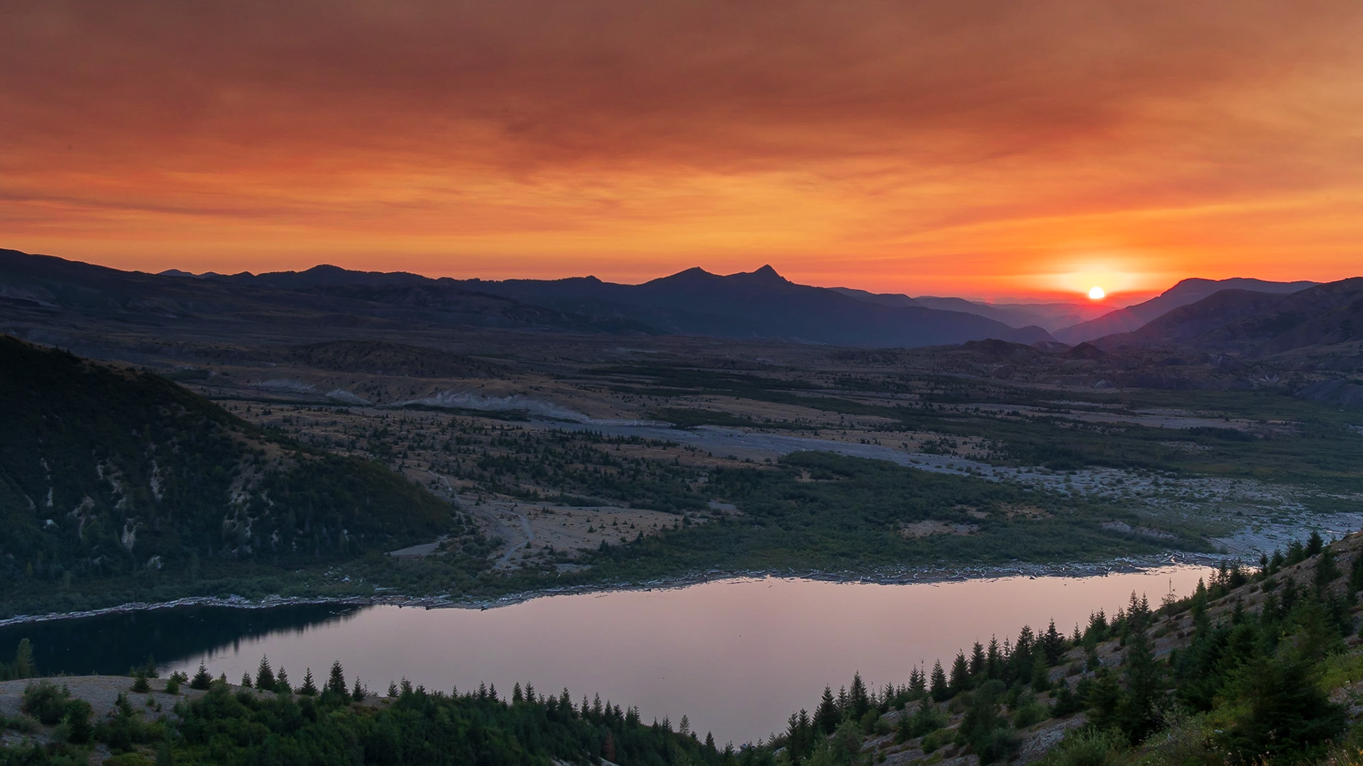 The setting sun lights up the smoky sky above Spirit Lake at the Mt St Helens National Monument.