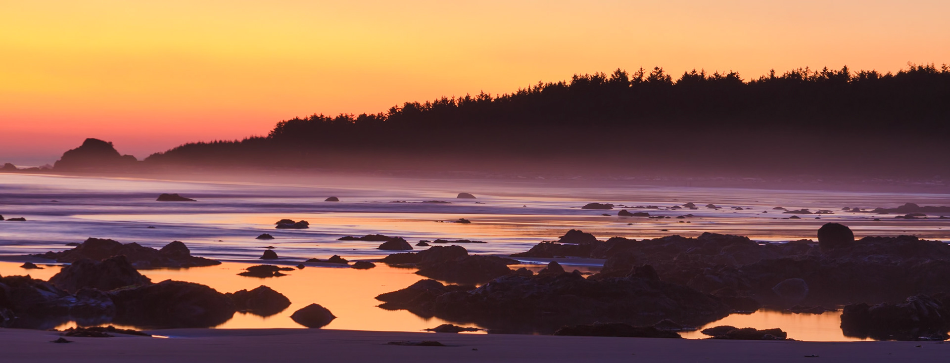 A mist rises from the bay while the setting sun creates a violet firestorm.