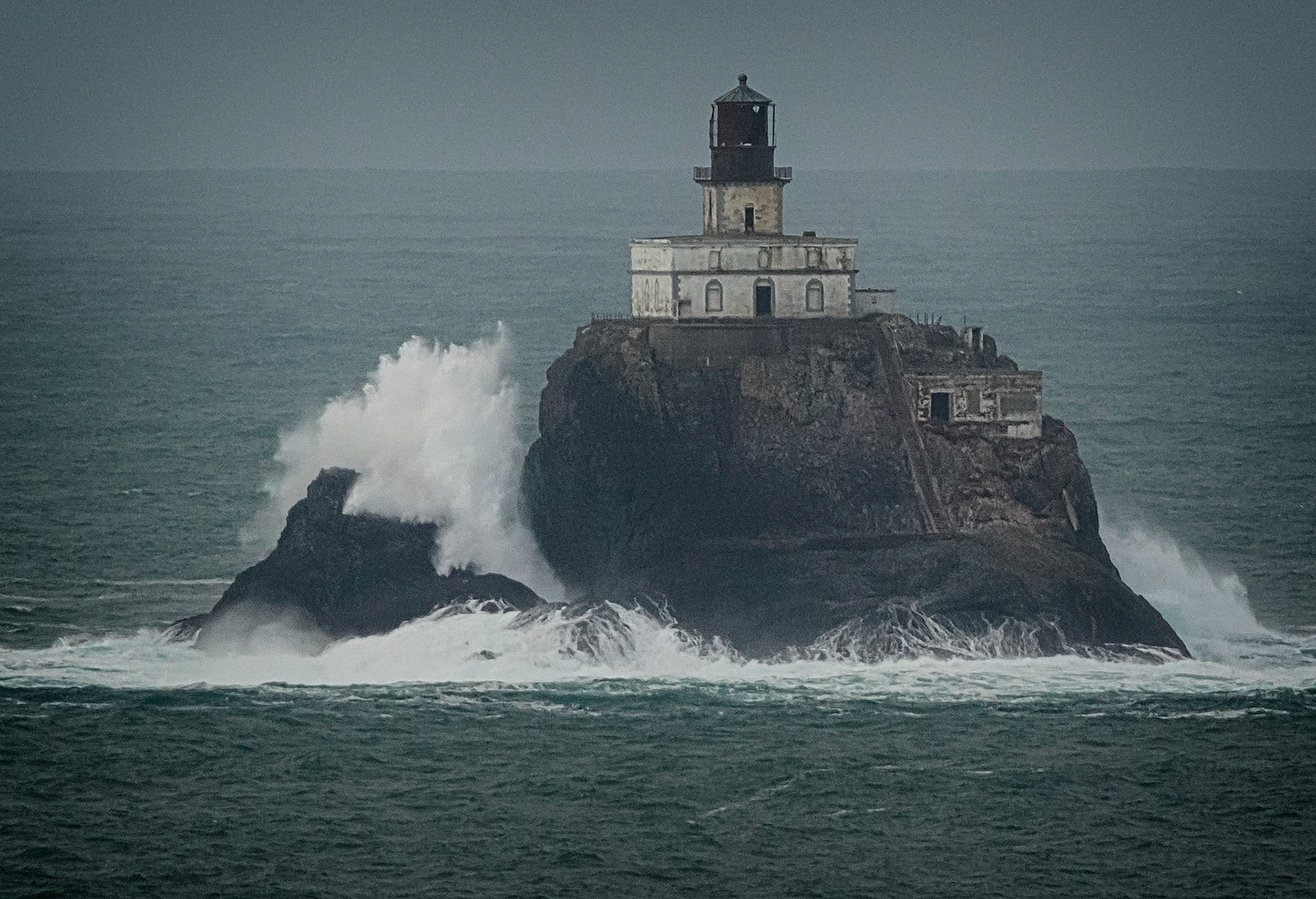 Waves crash against Tillamook Rock north of Cannon Beach Oregon.