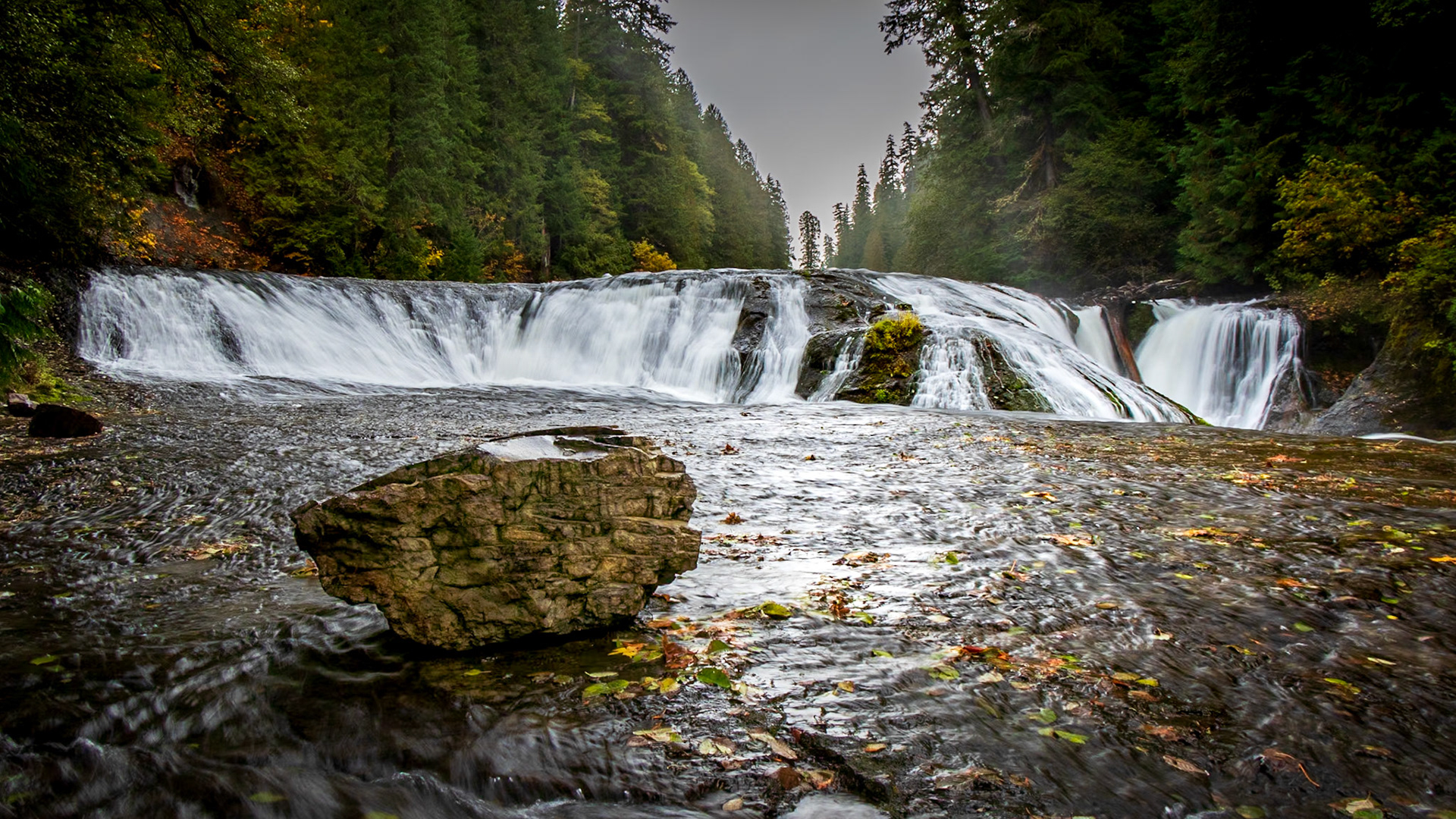 A large rock sits on the granite shelf below Middle Lewis River Falls
