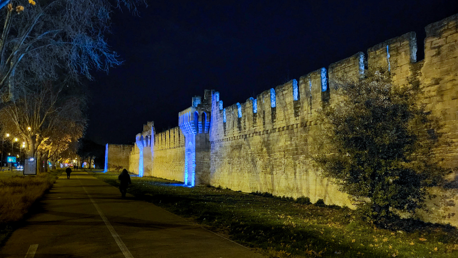 The wall surrounding the old town of Avignon is illuminated by night.