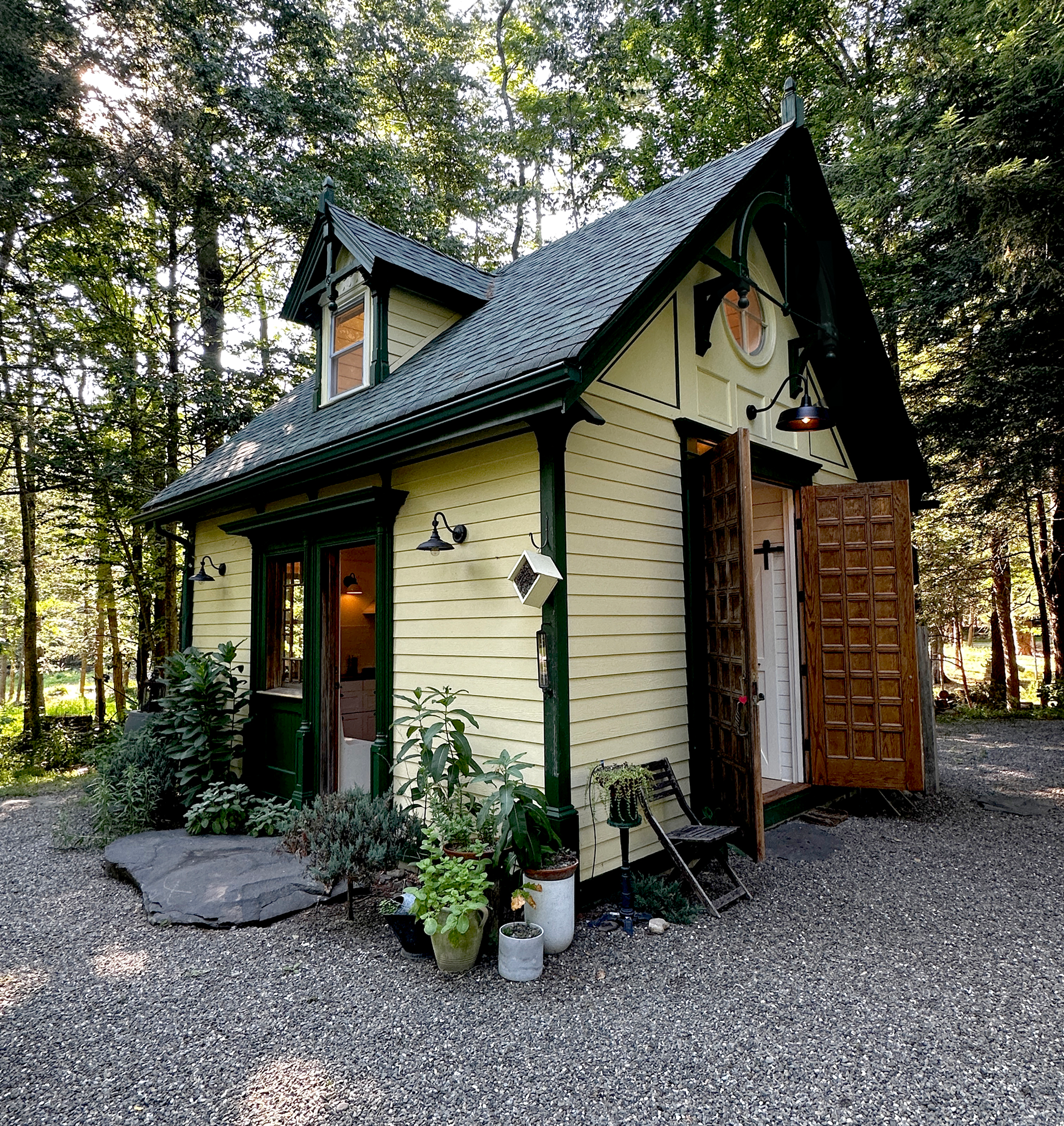 Catskill River Cottage in summer with its French oak doors open to the surrounding woods.