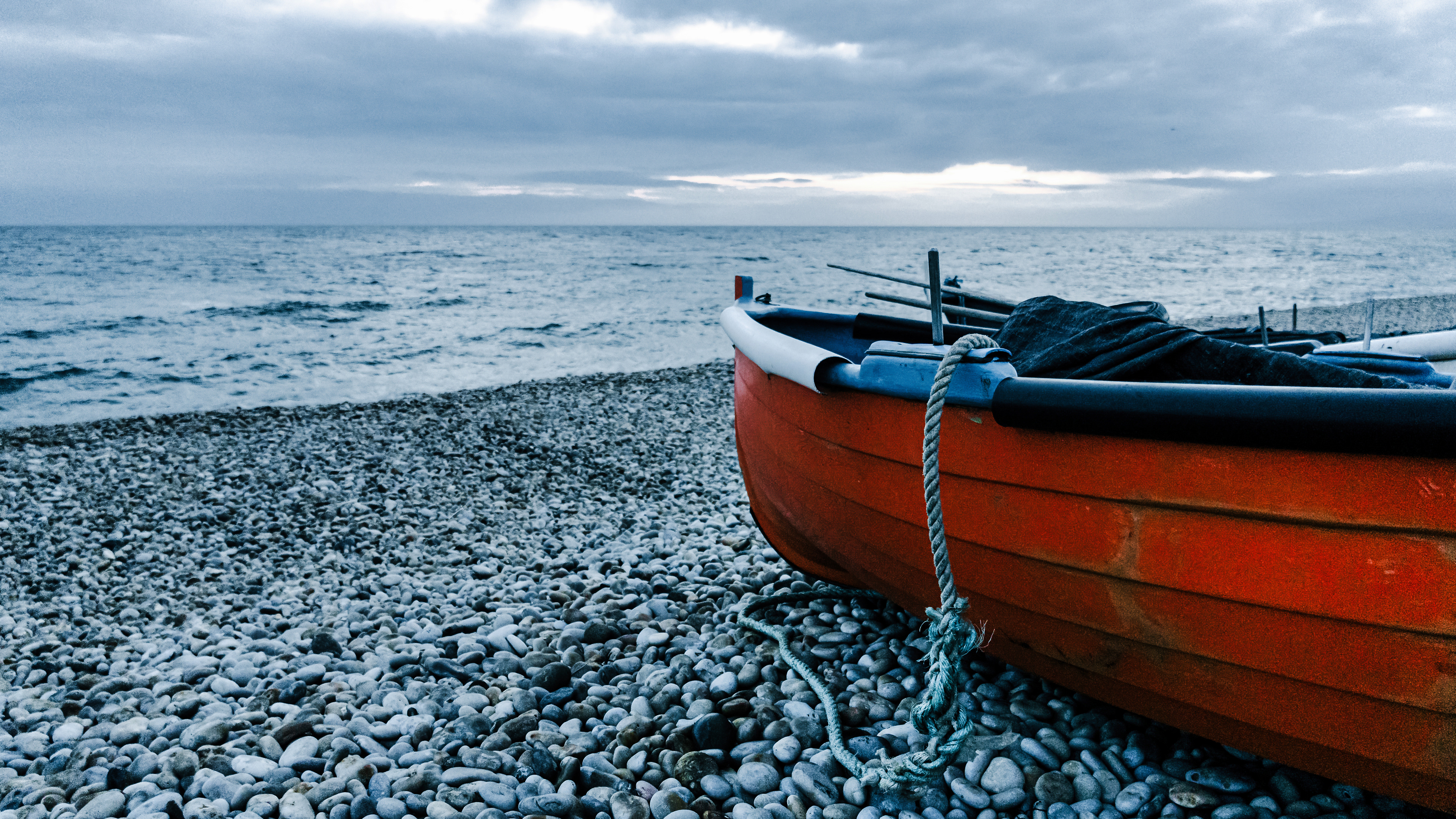 A quiet boat resting on a rocky shore.