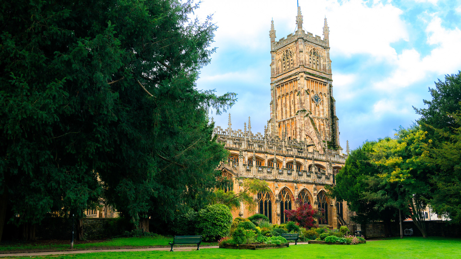 Timeless beauty in the heart of the Cotswold — the majestic tower of St. John the Baptist Church rises above the lush greenery of Cirencester, echoing centuries of English history.